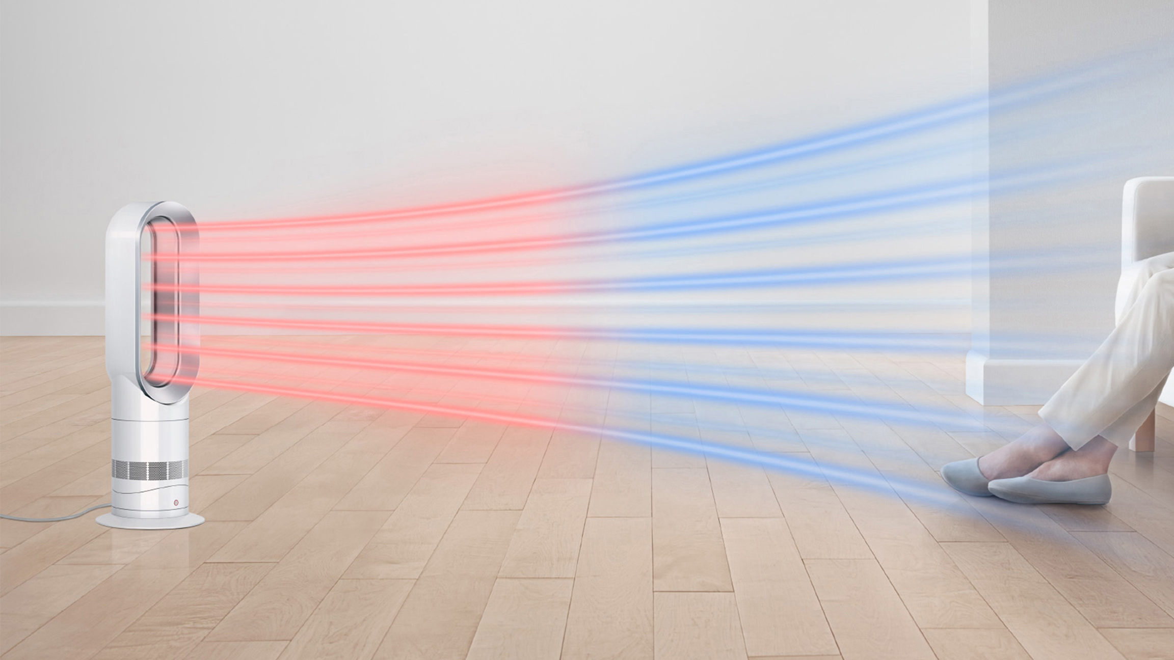 Un ventilador blanco sopla aire rojo y azul. Una persona está sentada cerca. Suelo de madera y pared blanca al fondo.