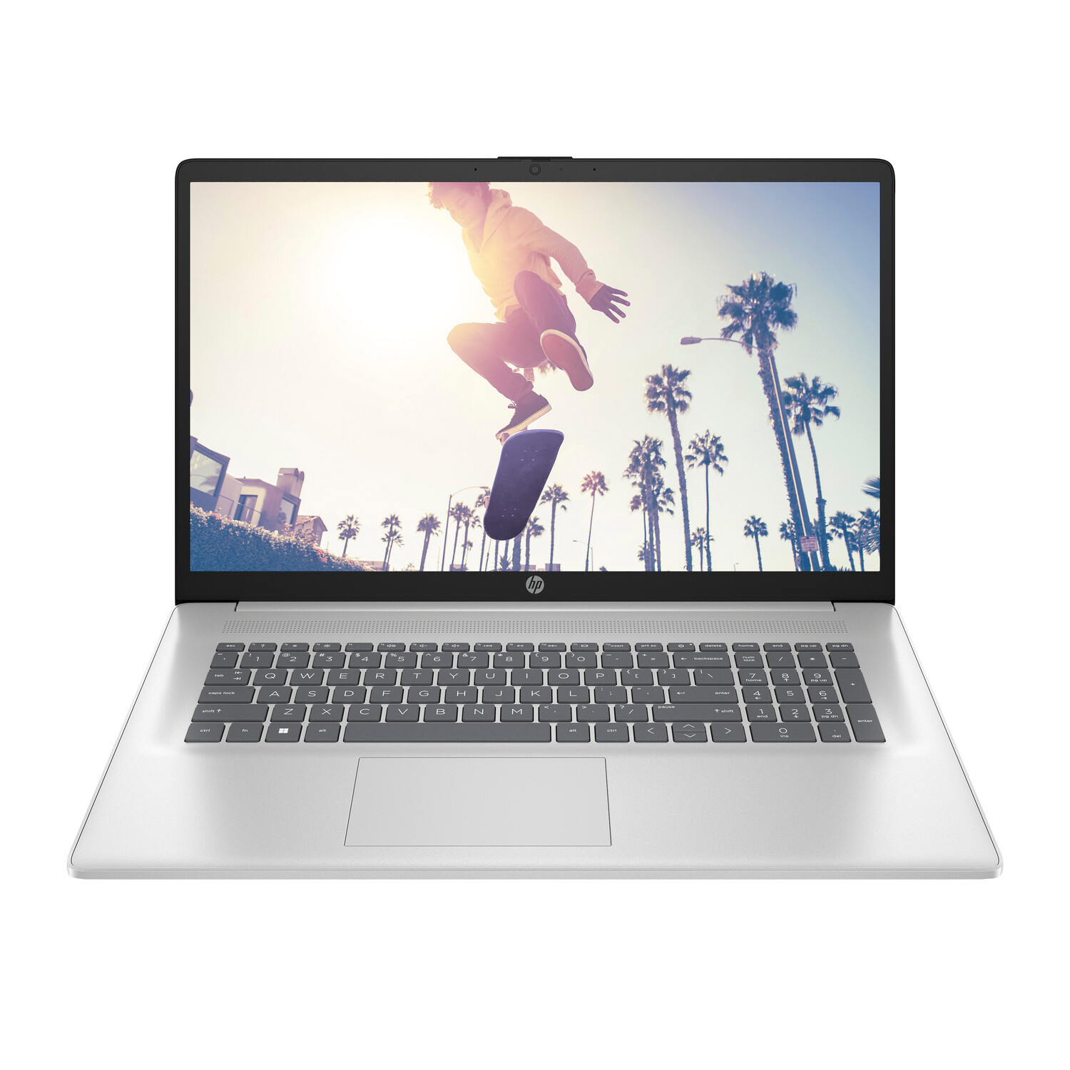 Laptop screen displays a person jumping on a skateboard. Palm trees and buildings are in the background. The laptop is open.