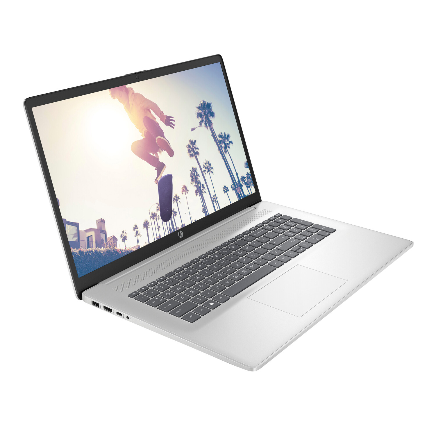 Silver laptop displays a person skateboarding. Palm trees and buildings are visible in the background. The laptop is angled.
