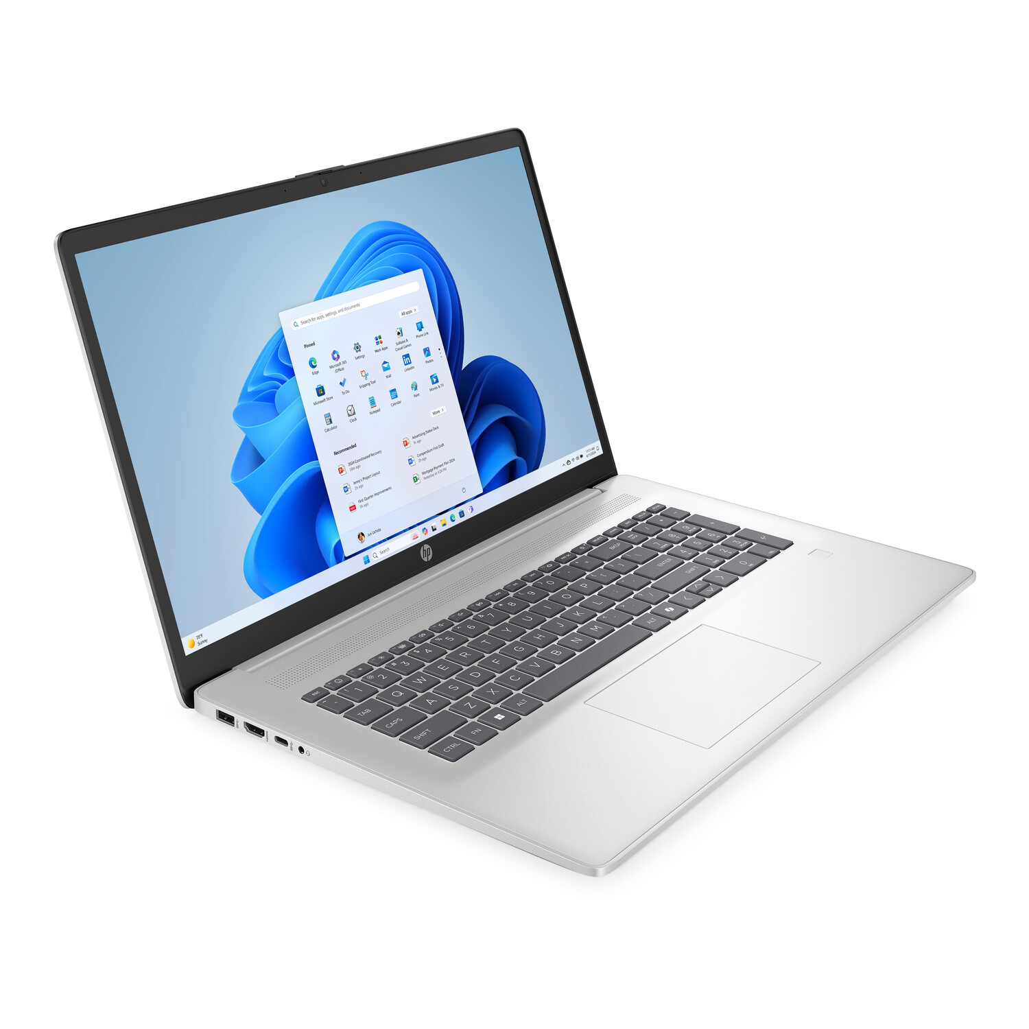 A silver HP laptop is open, displaying the Windows 11 interface. The screen shows the start menu with apps. The keyboard is visible.