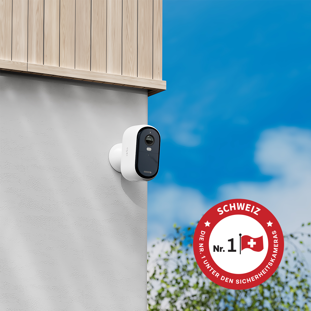 Una telecamera di sicurezza bianca montata su un muro grigio strutturato, con rivestimento in legno sopra. Un logo della bandiera svizzera è visibile a destra.