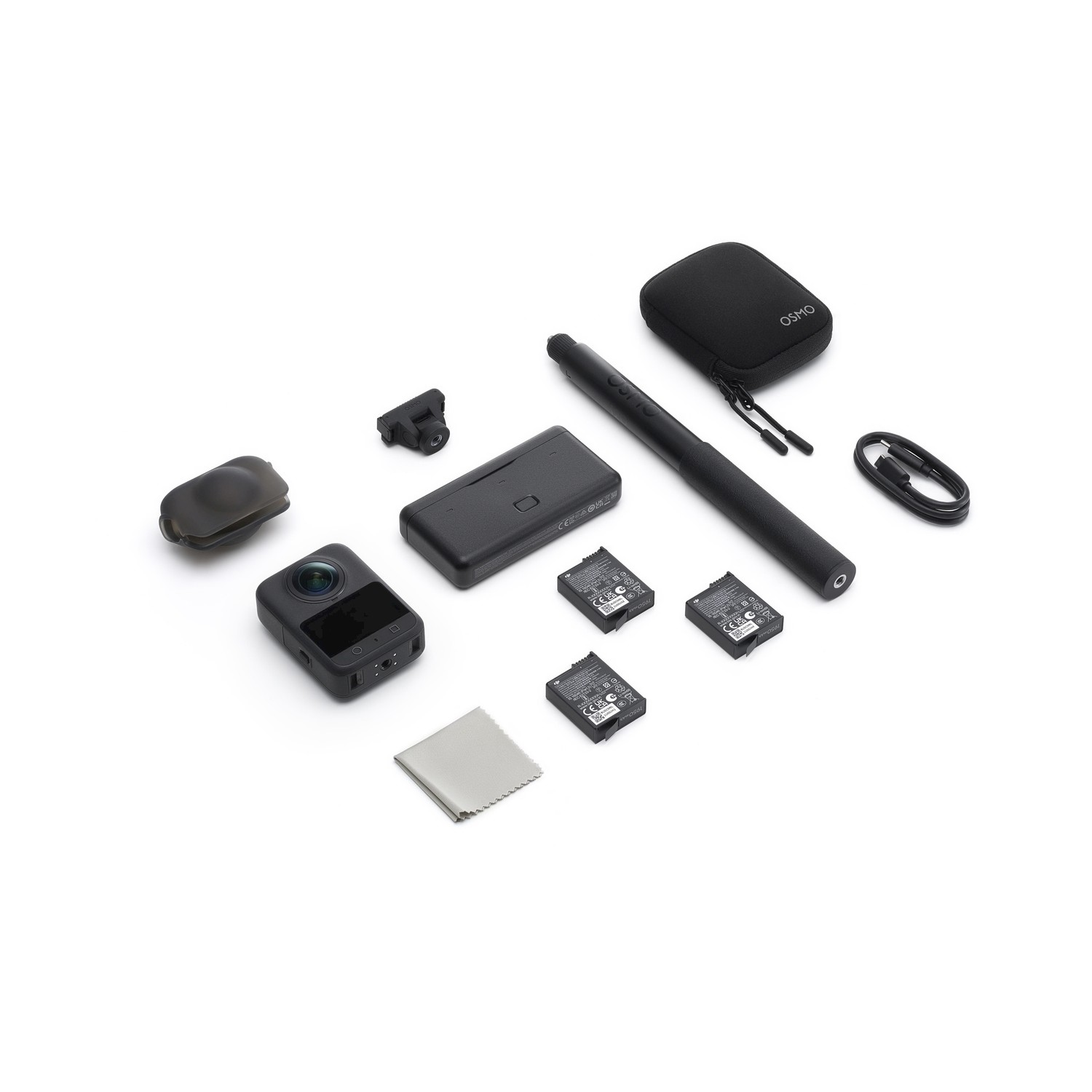 Una collezione di accessori per fotocamere neri, tra cui una fotocamera, batterie, custodia, penna e cavo di ricarica, disposti su una superficie bianca.