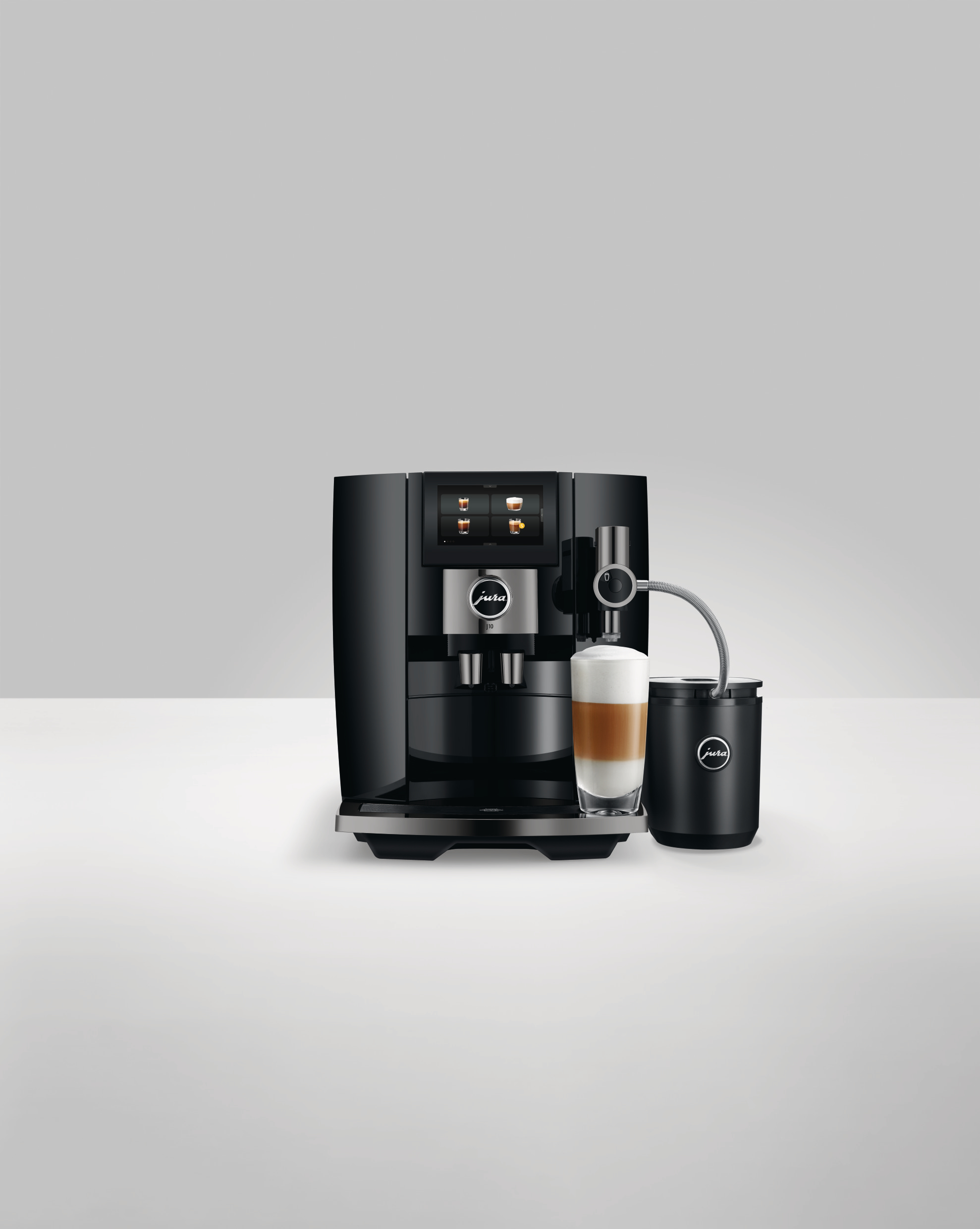 Schwarze Jura Kaffeemaschine mit einem Glas Latte. Die Maschine steht auf weißem Untergrund, mit weißem Hintergrund.
