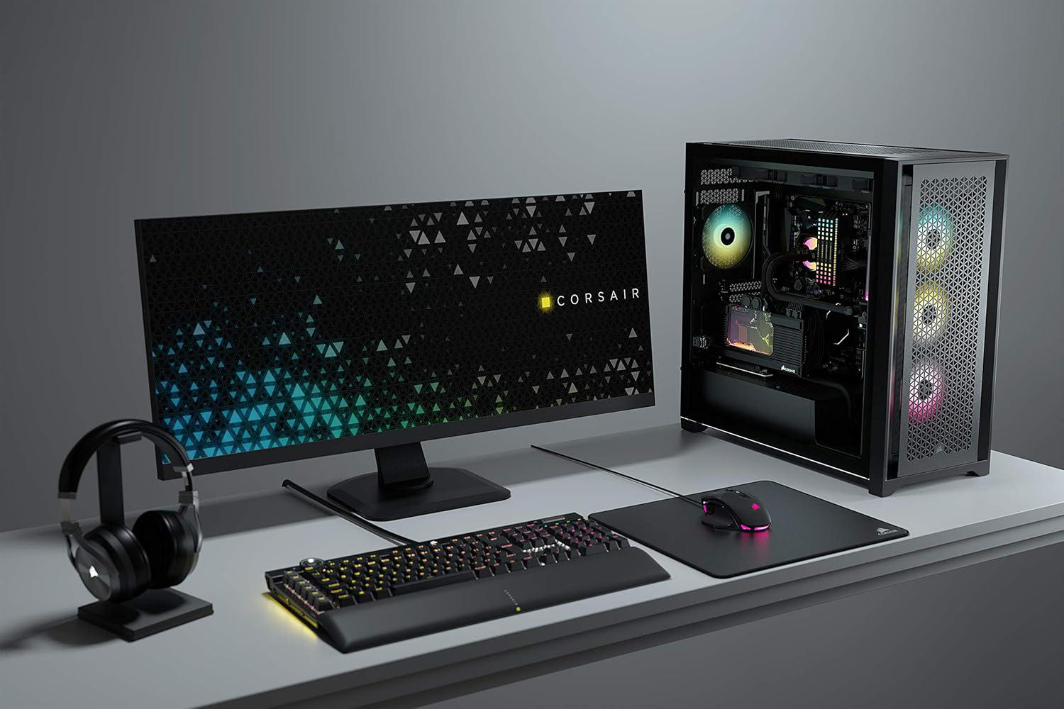 Gaming-Setup mit Monitor, PC, Tastatur, Maus und Kopfhörern. Corsair-Logo auf dem Monitor. RGB-Beleuchtung.