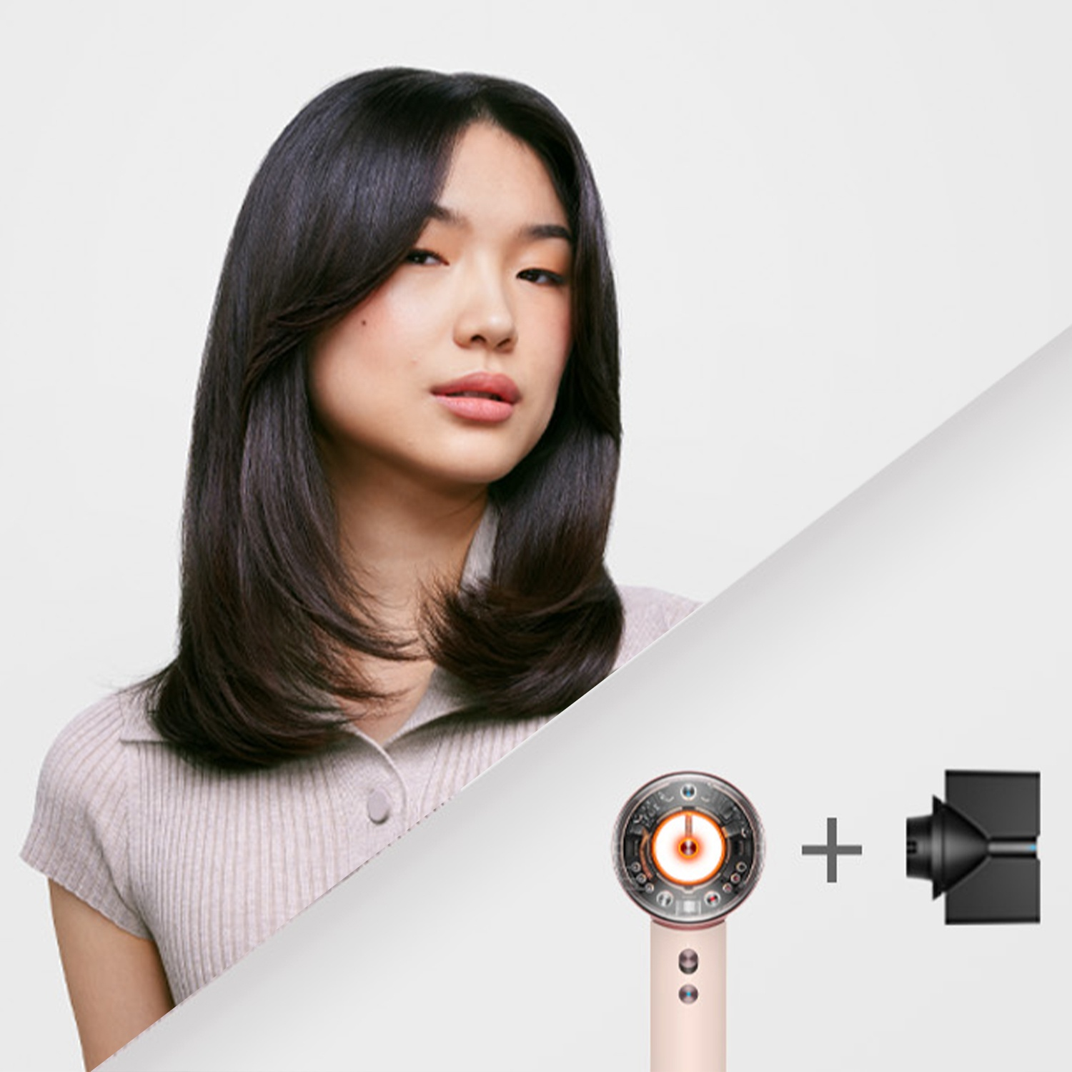 Donna asiatica con capelli scuri e un asciugacapelli Dyson con un accessorio. Lo sfondo è bianco e diviso diagonalmente.