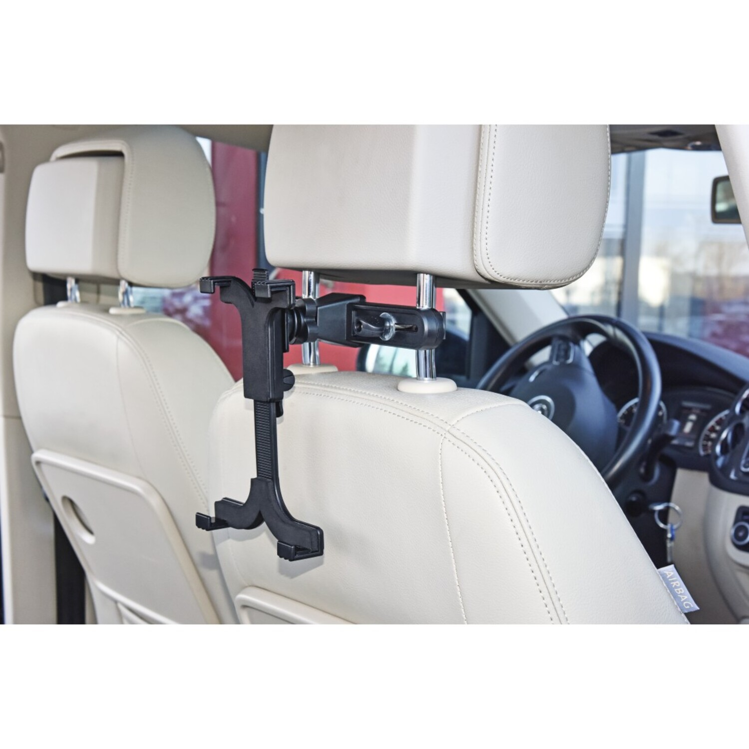 Un support de tablette noir est monté sur l'appuie-tête d'une voiture. Des sièges en cuir beige et un volant sont visibles en arrière-plan.