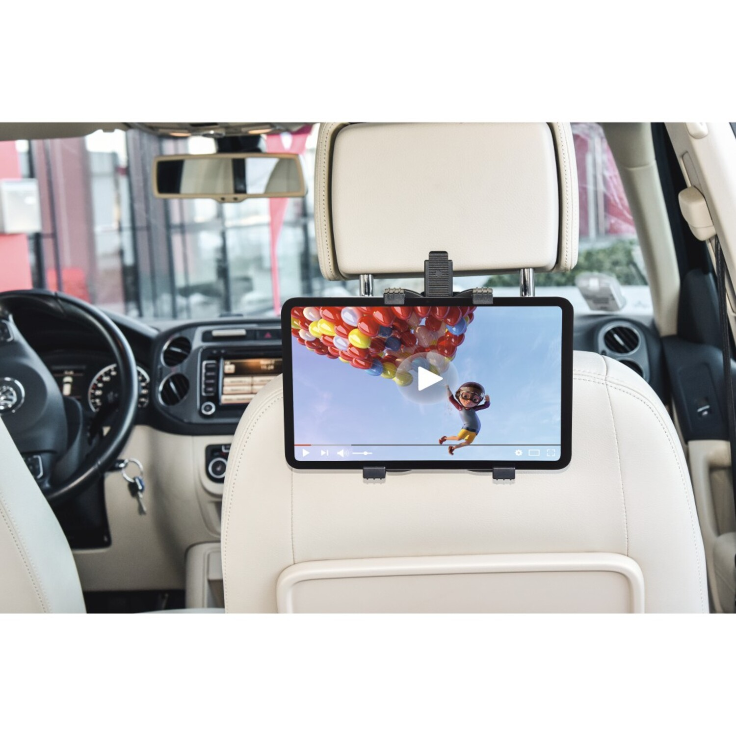 Tablette diffusant une vidéo, montée sur un siège de voiture. La vidéo montre un personnage de dessin animé volant avec des ballons. L'intérieur de la voiture est visible.