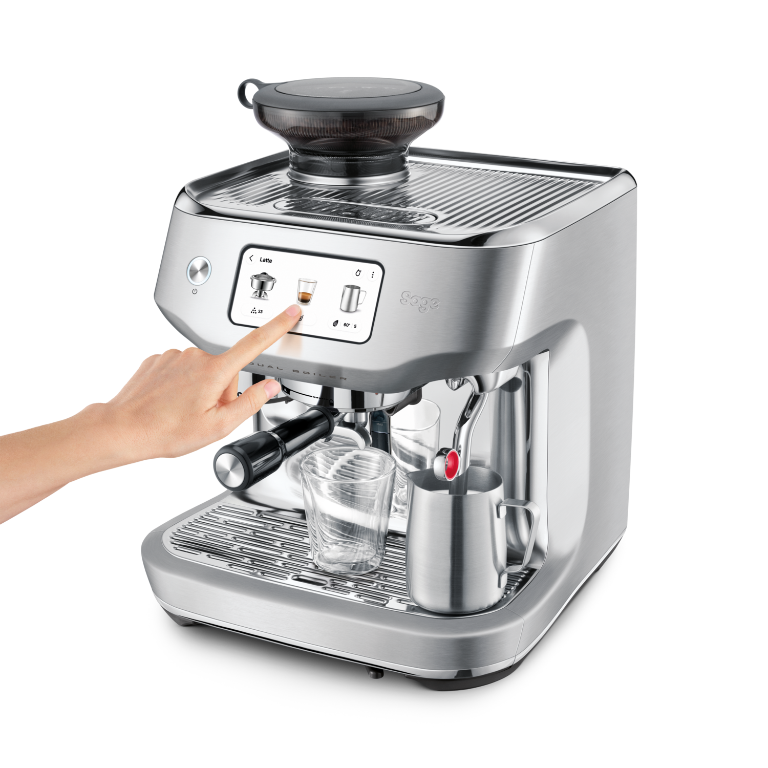 A silver espresso machine with a hand touching the screen. There is a glass, a milk jug, and a coffee bean grinder on top.