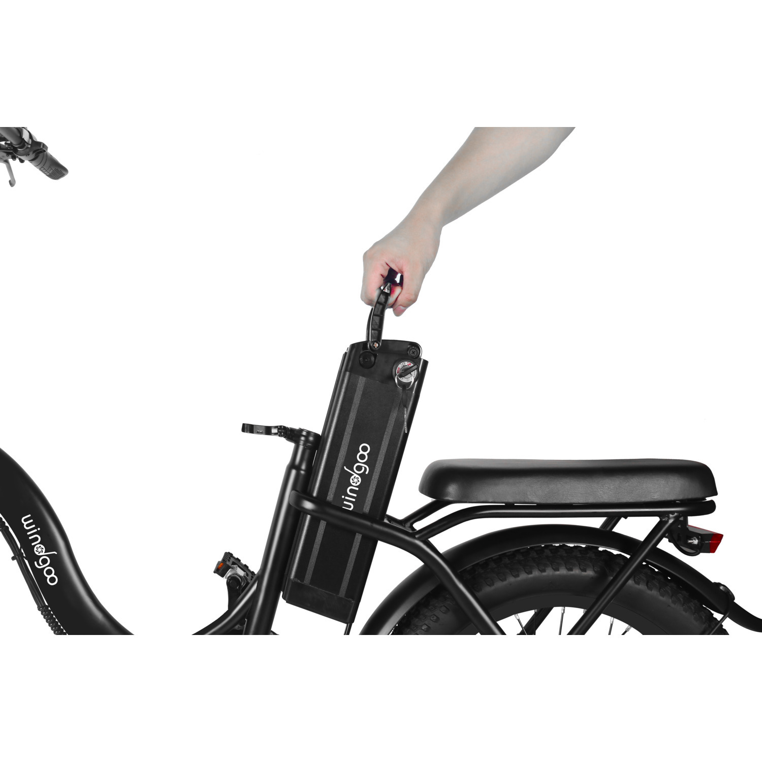 Une main tenant une batterie sur un vélo électrique noir. Le vélo a des pneus, une selle et un cadre noirs. Le fond est blanc.