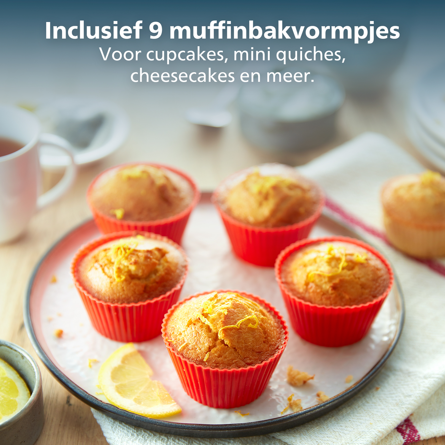 Six muffins in red cups on a plate, a lemon slice, a cup of tea and a white background.