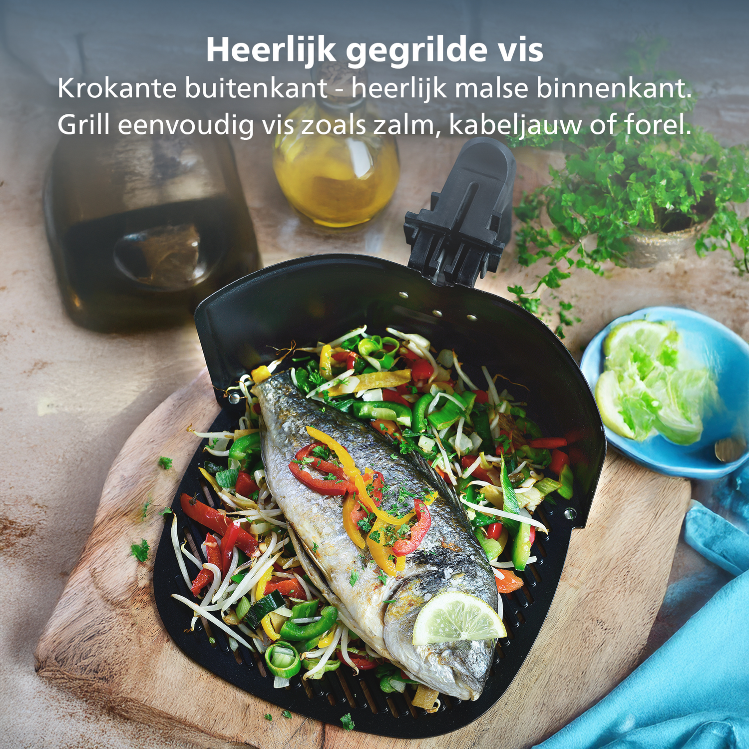 Poisson grillé avec légumes dans une poêle noire, une tranche de citron et herbes. Fond avec huile, plante et tissu bleu.