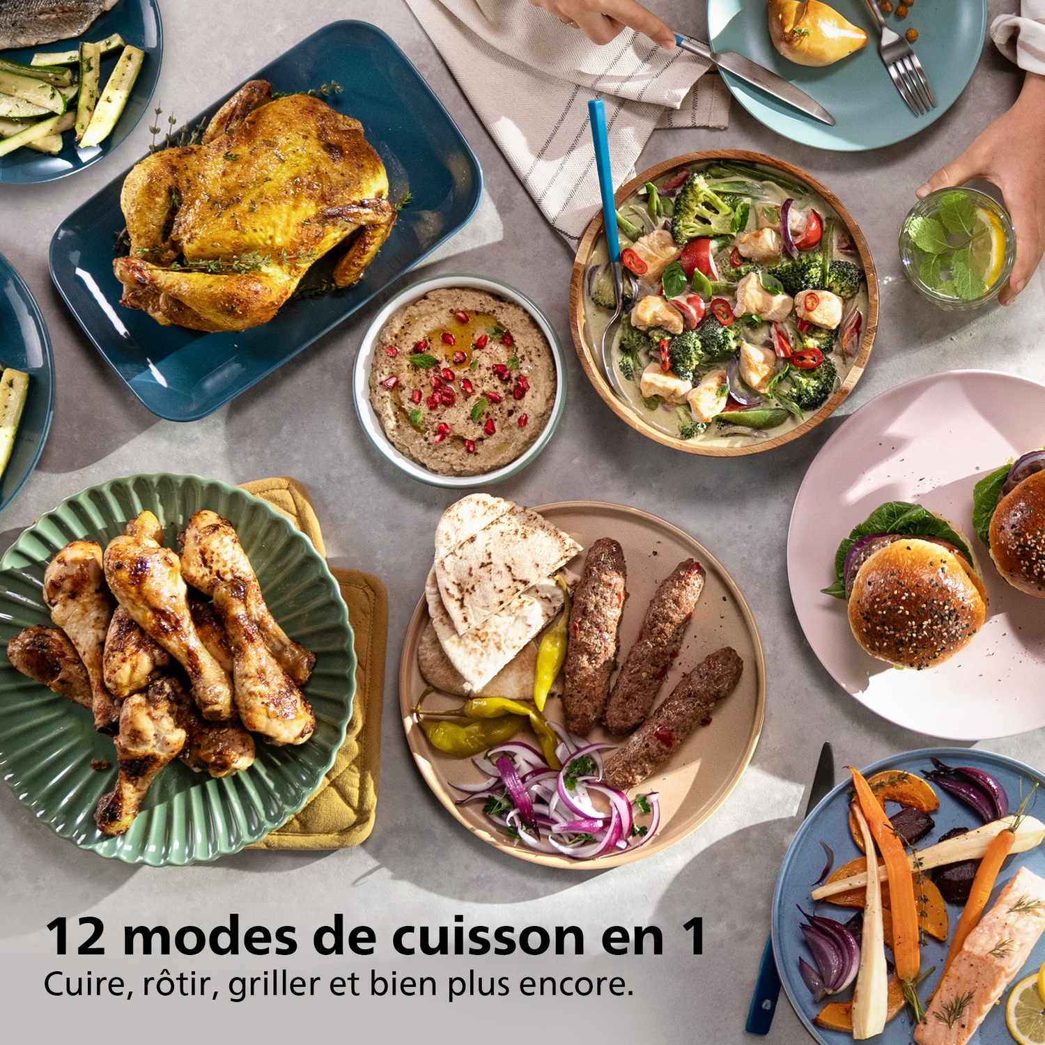 Une table avec divers plats : poulet rôti, soupe, kebabs, burgers, légumes et sauces. Mains se servant.