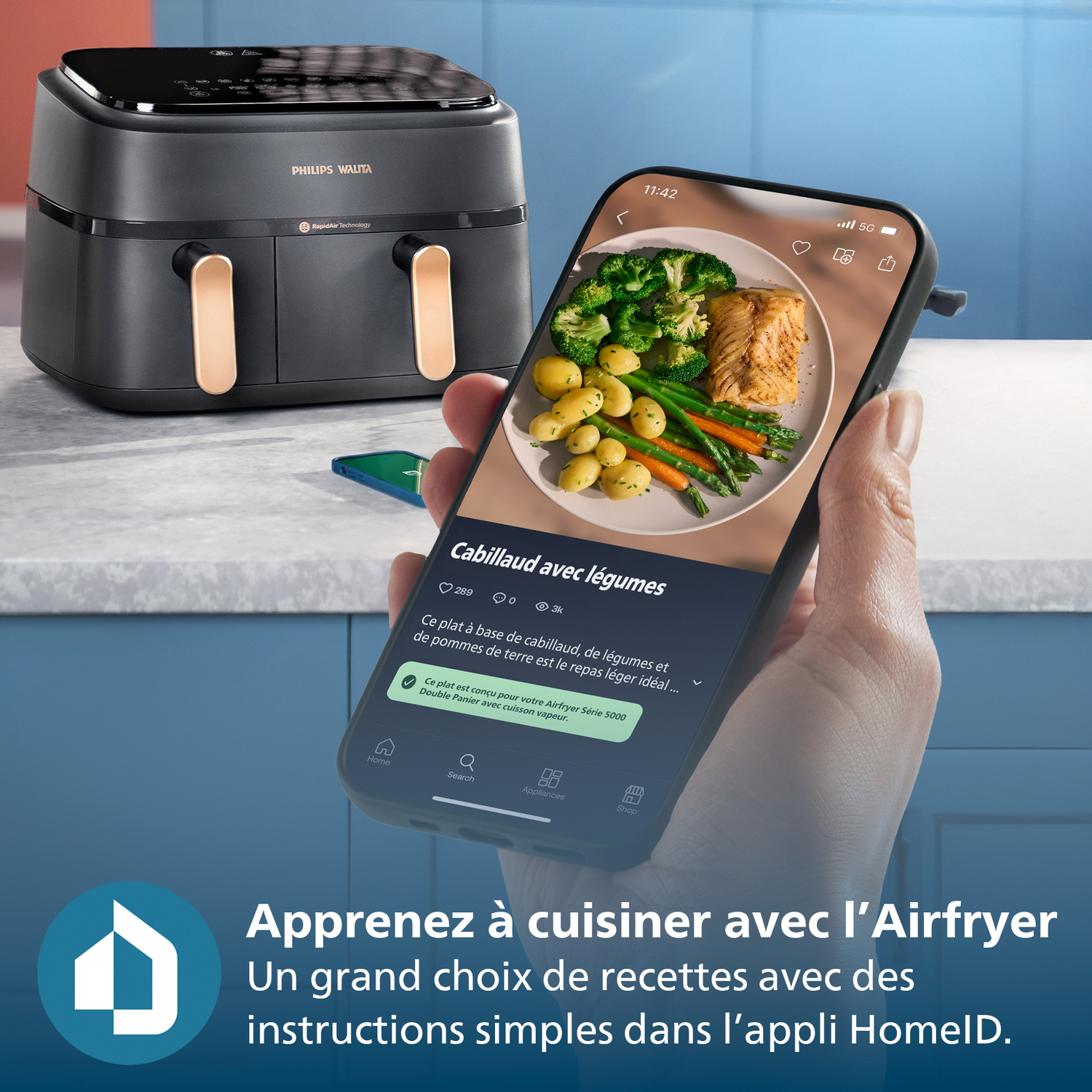 Un airfryer à côté d'un téléphone affichant un repas : cabillaud avec légumes. Le téléphone est tenu par une personne.