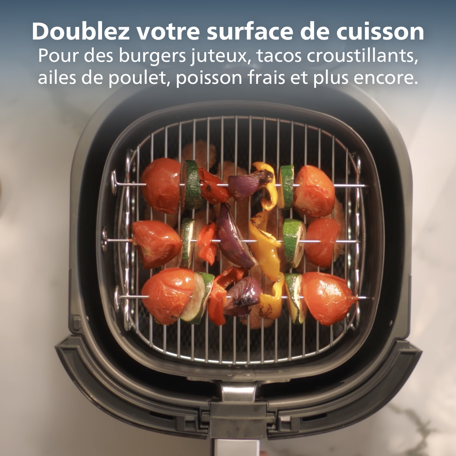 Een airfryer met spiesjes van gegrilde groenten en tomaten. De airfryer is open. Tekst bovenaan.