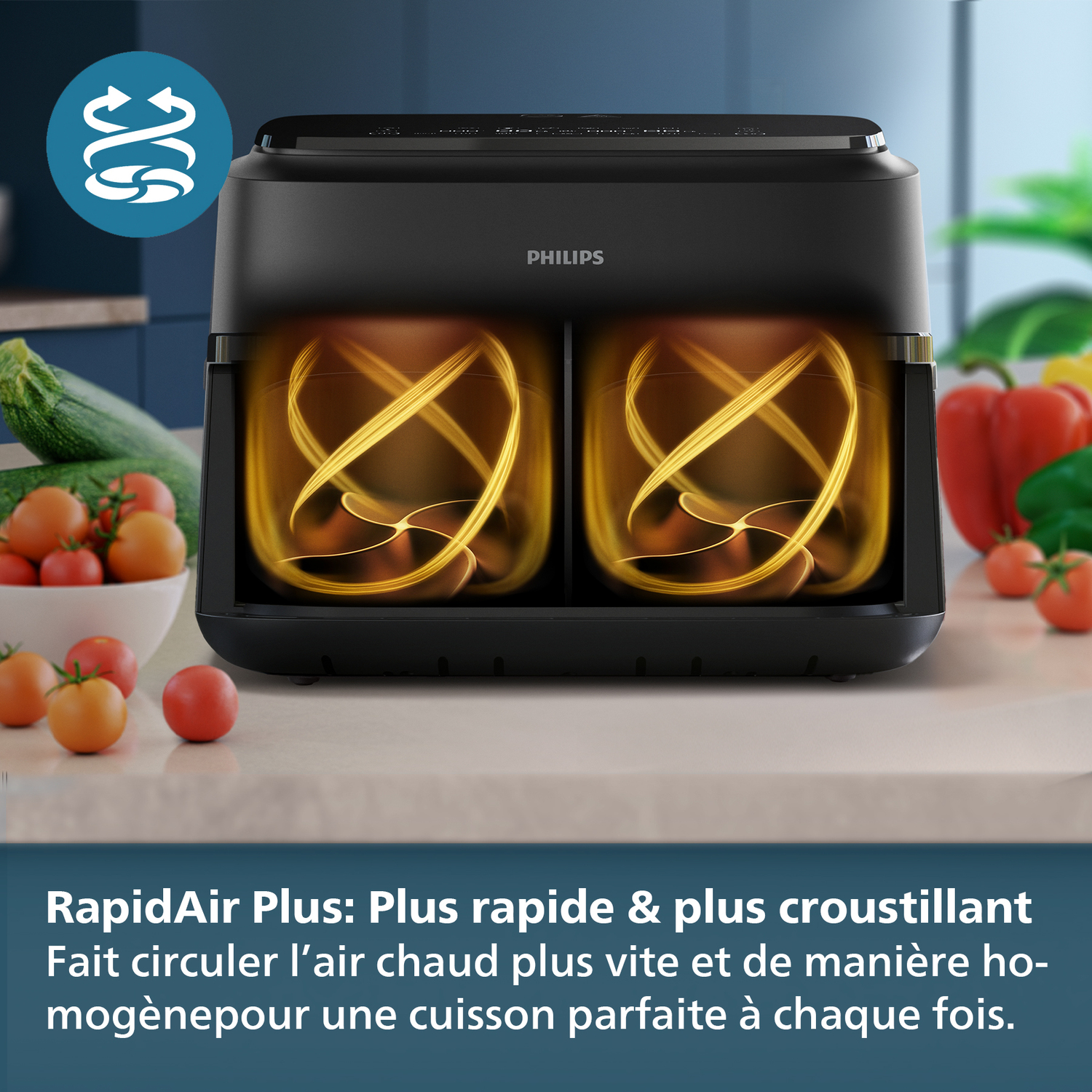 Een zwarte Philips heteluchtfriteuse met twee compartimenten. Binnenin een wervelend oranje lichteffect. Groenten en tomaten op de achtergrond.