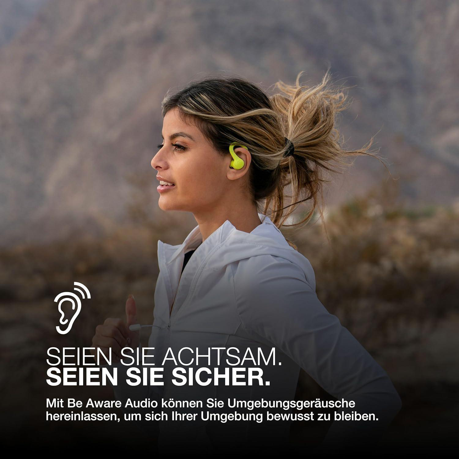 Eine Frau rennt mit gelben Ohrhörern. Sie trägt eine weiße Jacke und hat ihr Haar zurückgebunden. Text: Sei achtsam, sei sicher.