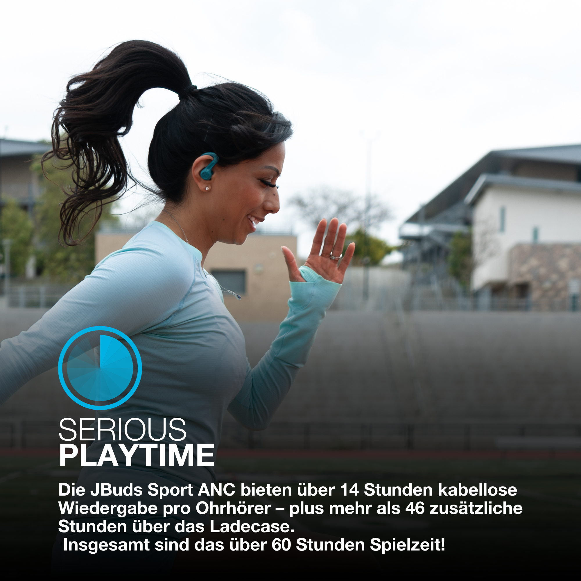 Eine Frau läuft im Freien und trägt türkisfarbene Ohrhörer. Text: SERIOUS PLAYTIME. Das Bild bewirbt JBuds Sport ANC-Kopfhörer.