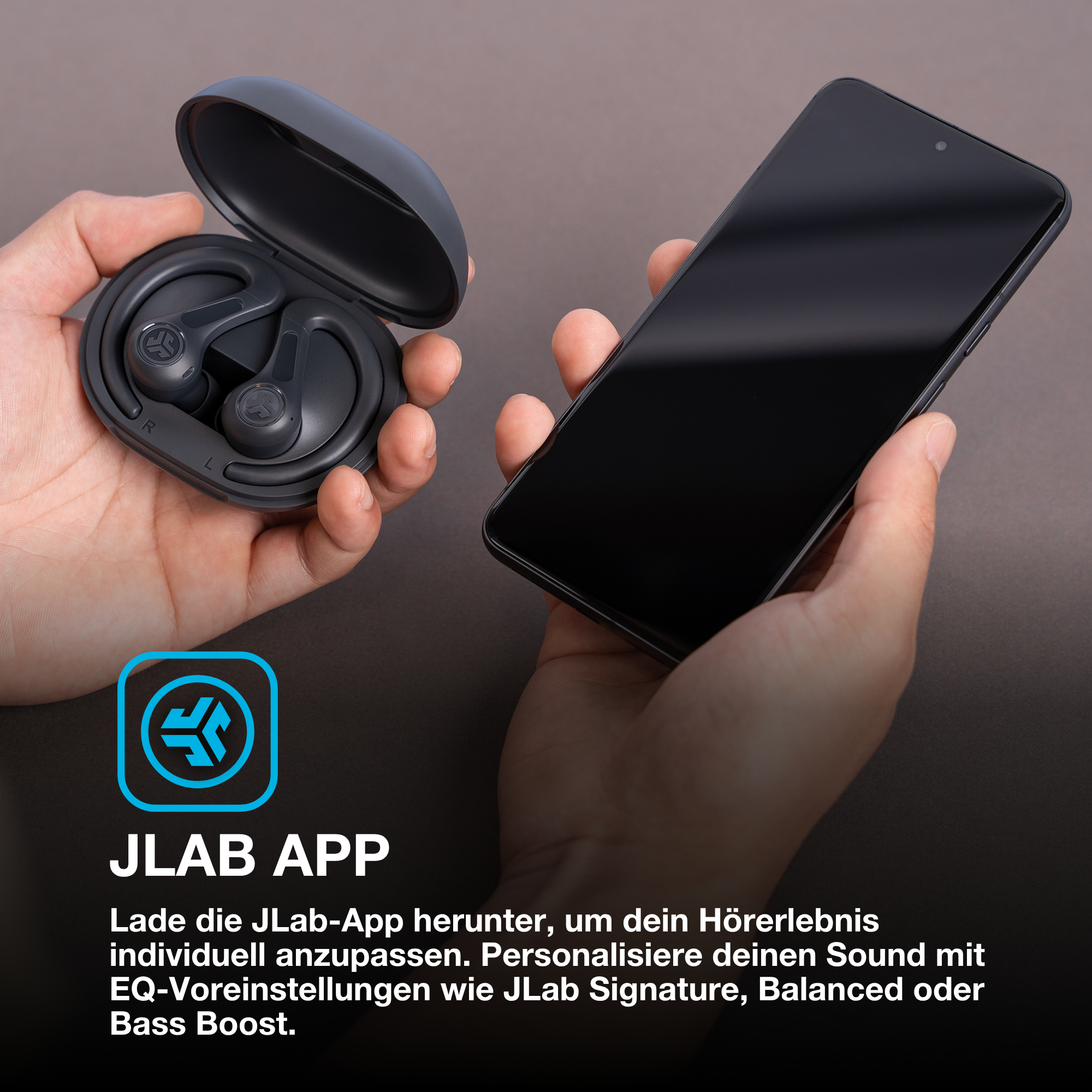Hände halten Ohrhörer und ein Telefon. Ohrhörer in einem Etui. Telefonbildschirm ist schwarz. JLab App Logo unten.