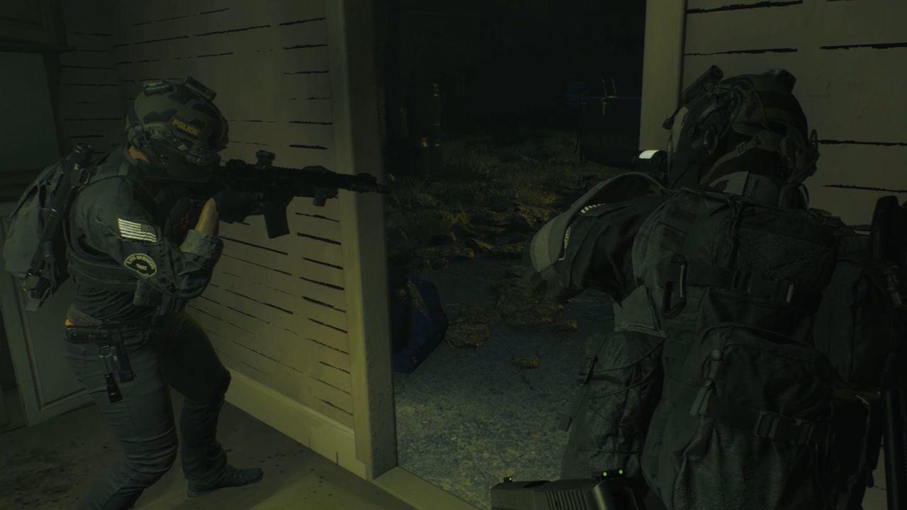 Zwei Polizisten in taktischer Ausrüstung in einem Gebäude, die mit Waffen zielen. Einer schaut aus einer Tür, der andere steht bereit.