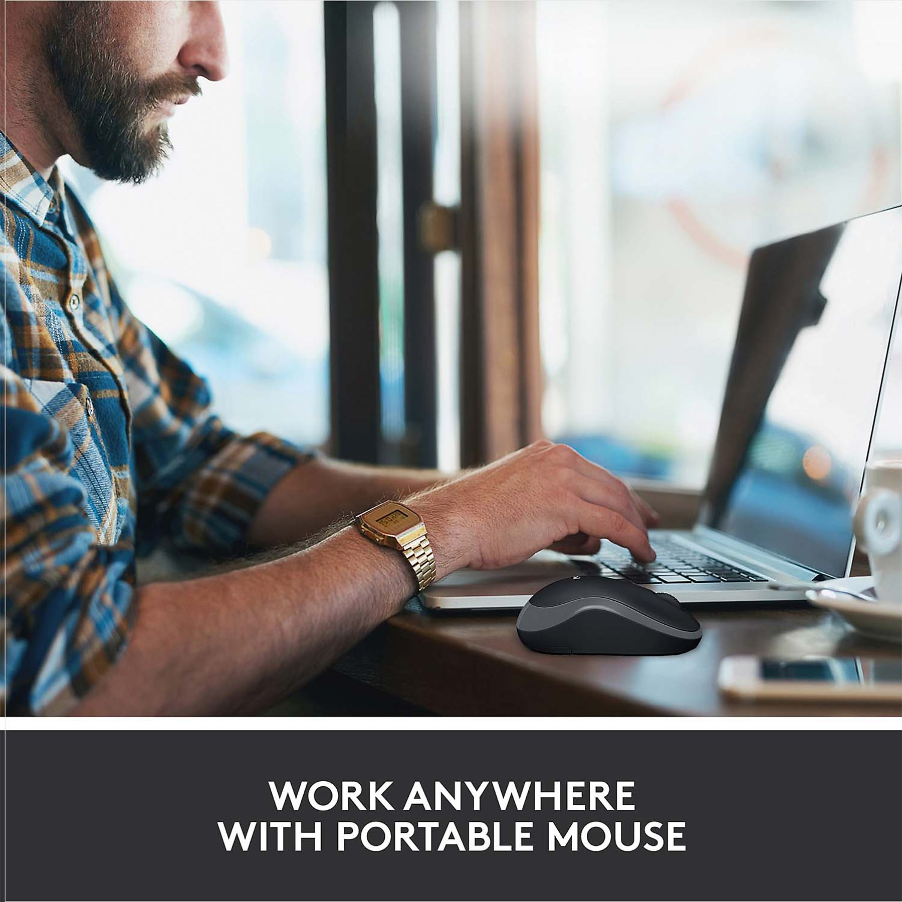 Un uomo usa un laptop e un mouse su un tavolo. Indossa un orologio e una camicia a quadri. La scena è in un bar.