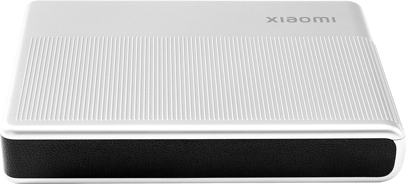 Egy ezüst készülék a tetején a 'xiaomi' szóval. A felső felületen függőleges vonalak vannak. Az alja fekete és texturált.