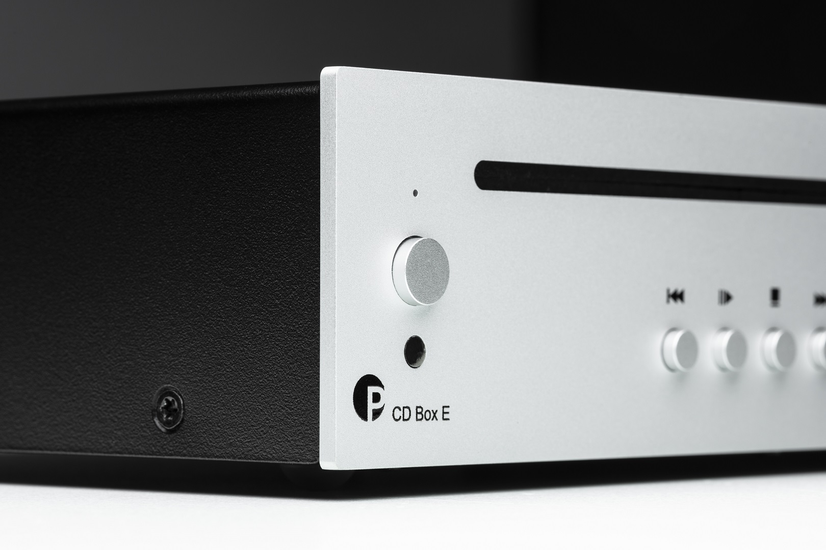 Ein silberner und schwarzer CD-Player. Die silberne Vorderseite hat einen Drehregler, Knöpfe und einen Schlitz. Die schwarze Seite hat eine Schraube.