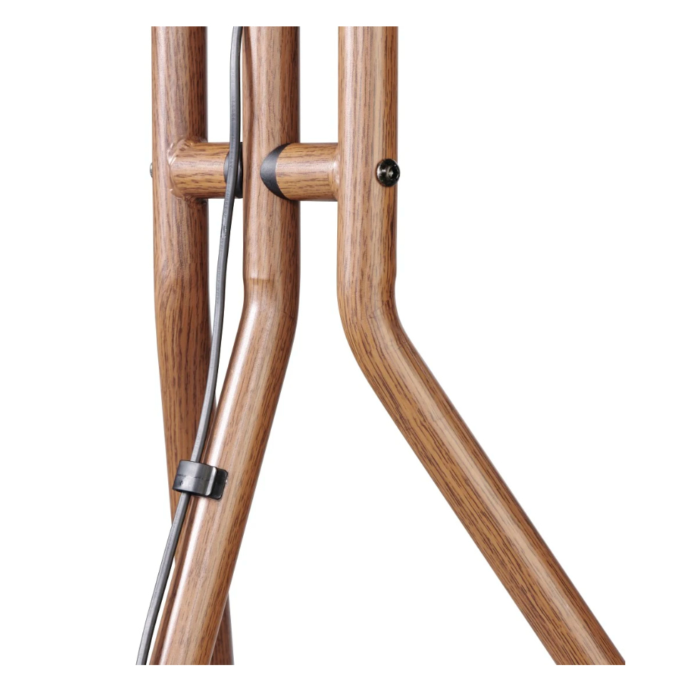 Primer plano de una base de lámpara de madera. Postes de madera marrón con un cable negro que los atraviesa. Se ve un tornillo y una pinza negra.