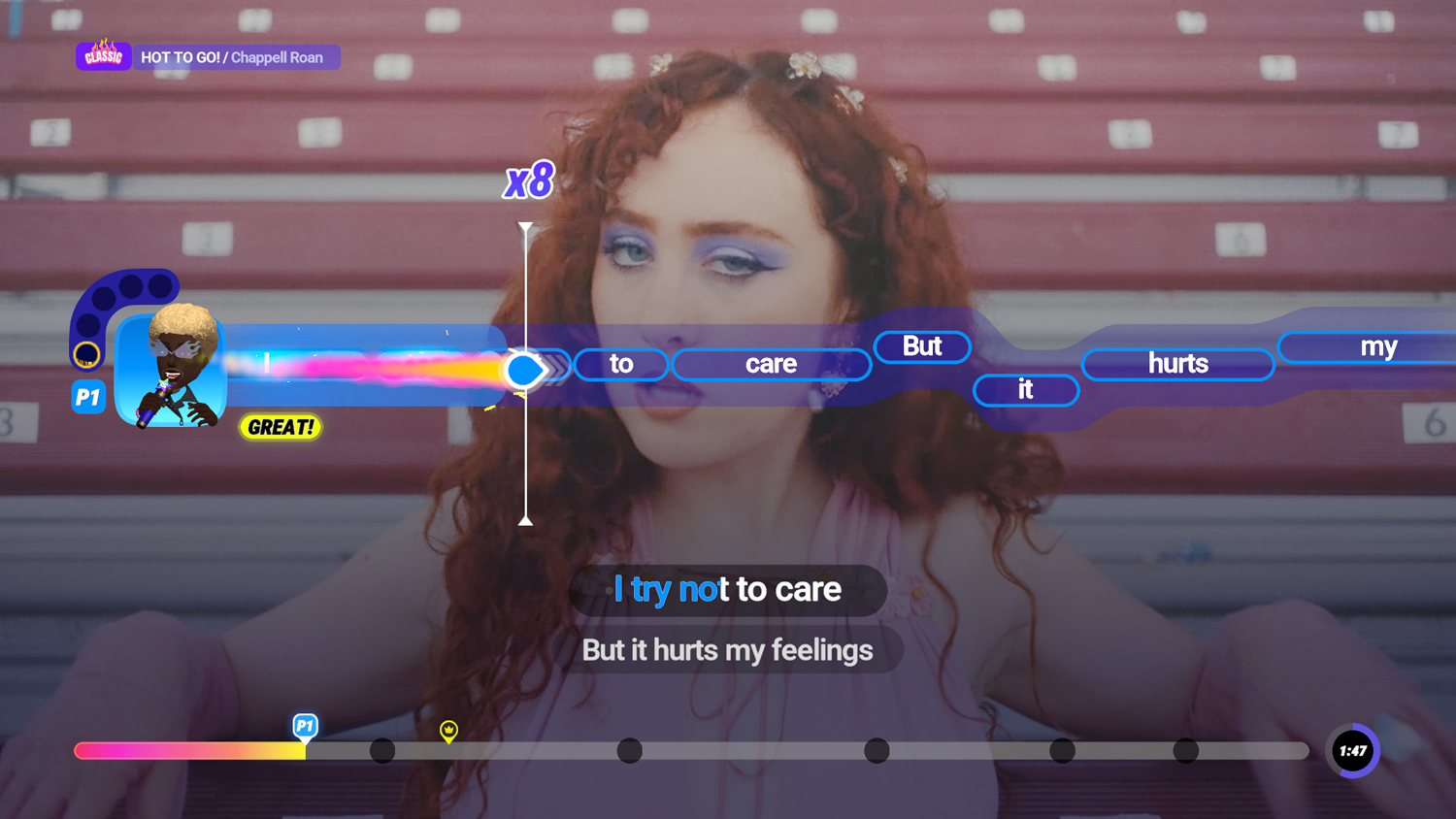 Una donna dai capelli rossi canta al karaoke. L'interfaccia di gioco mostra il testo della canzone e un misuratore delle prestazioni. Lo sfondo sono delle gradinate.