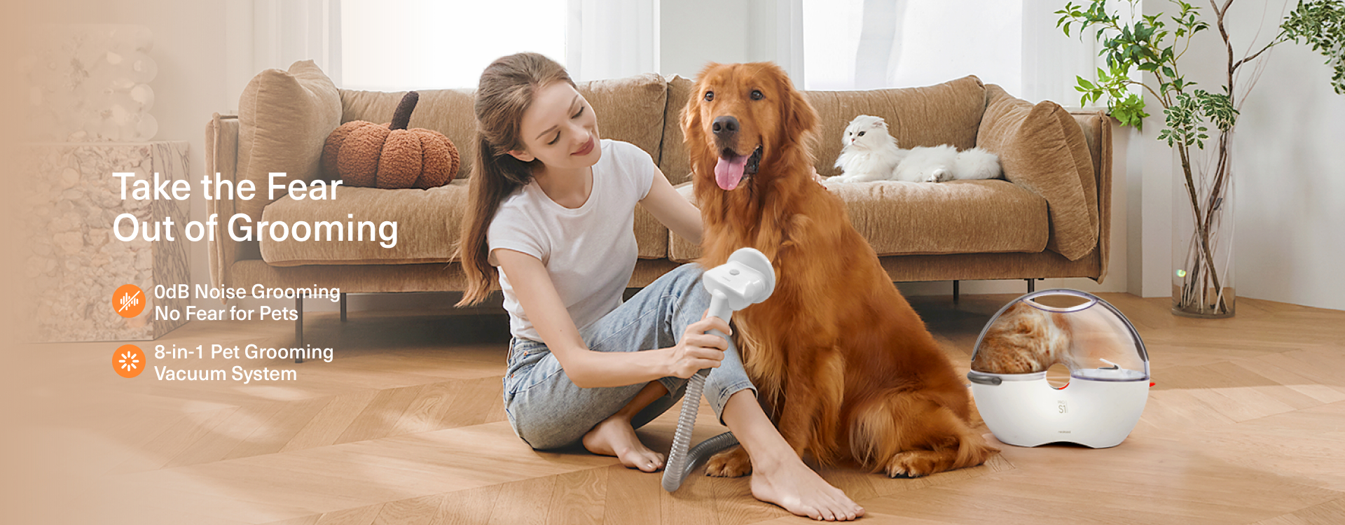 Eine Frau pflegt einen Golden Retriever mit einem Staubsauger. Eine weiße Katze ruht auf dem Sofa. Eine Katze ist in einem Pflegegerät.