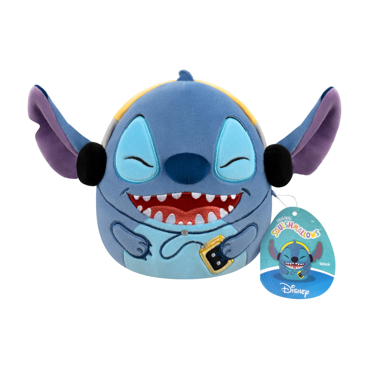 Peluche di Stitch con cuffie, sorridente. Corpo blu, orecchie grandi. Etichetta allegata. Sfondo bianco.