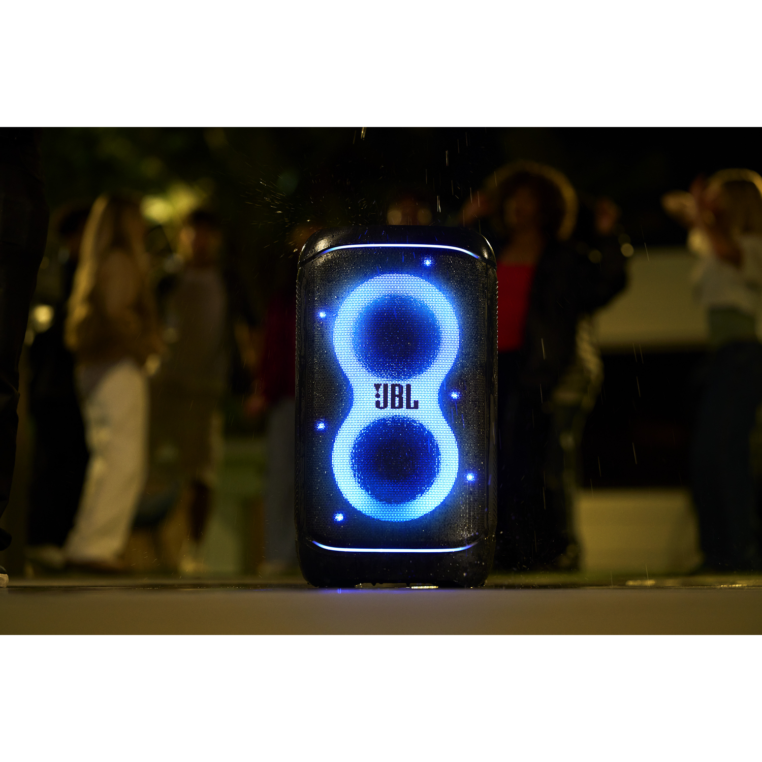 Een JBL-luidspreker met blauw gloeiende lichten, voor wazige mensen 's nachts met regen.