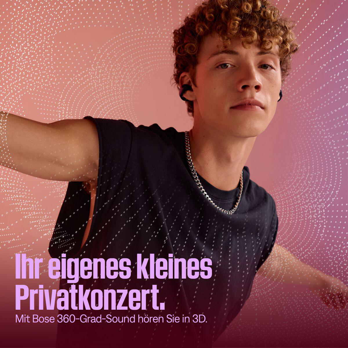 Ein junger Mann mit Locken trägt Ohrhörer und eine Kette. Der Hintergrund ist rosa und lila mit weißen Punkten.