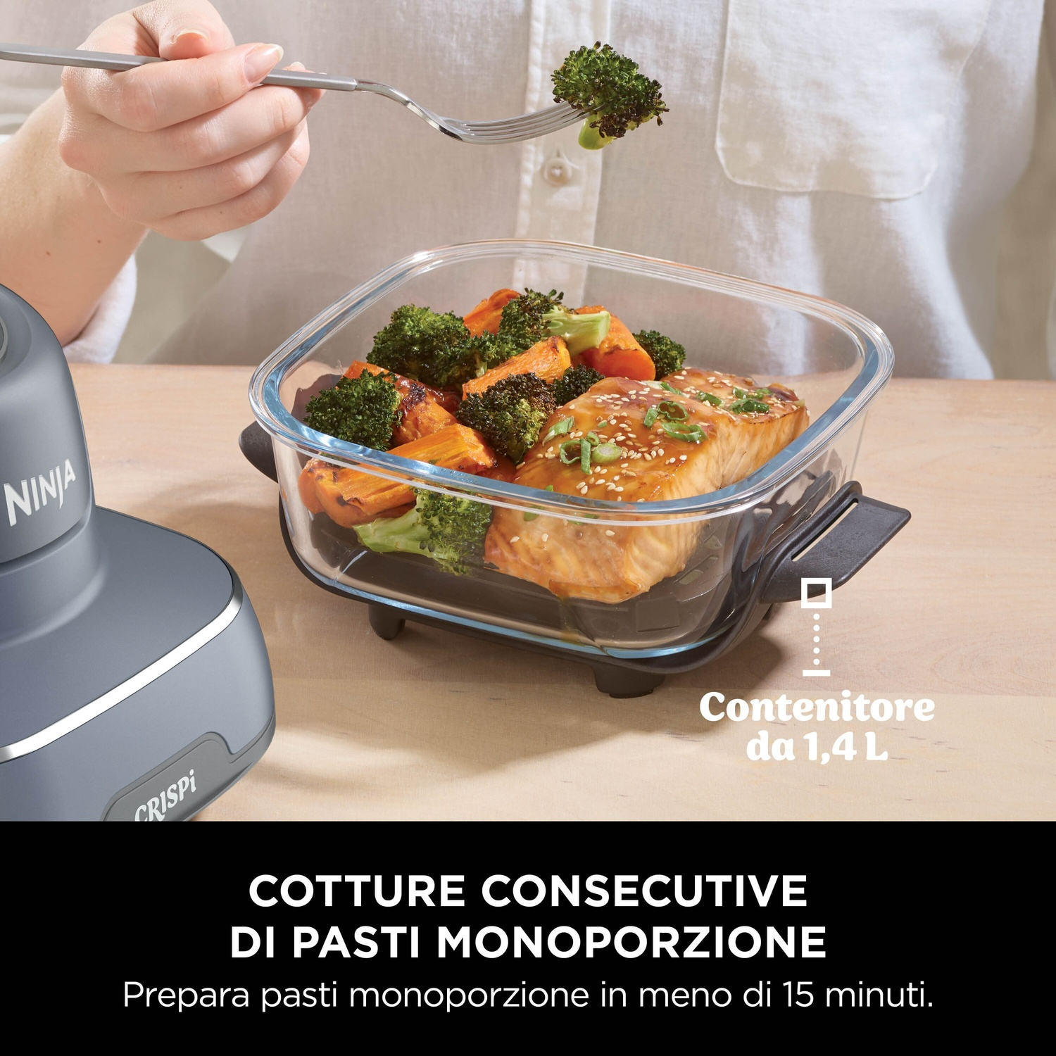 Un contenitore di vetro con cibo, tra cui pesce e verdure. Una persona tiene una forchetta con broccoli. Ninja Crispi visibile.