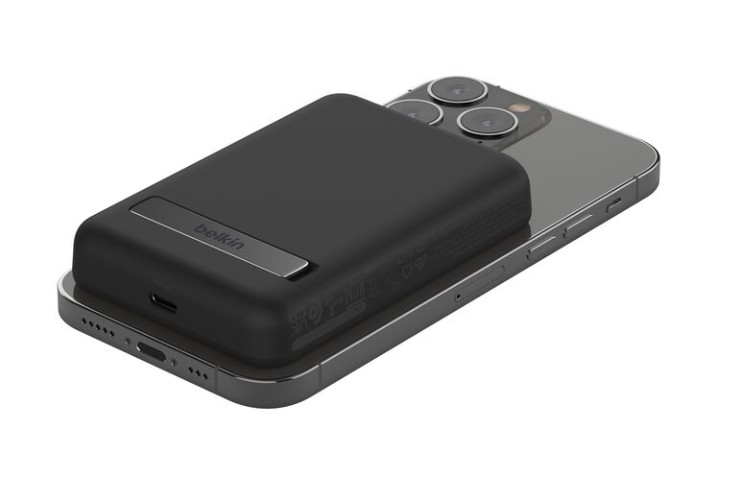 Siyah Belkin taşınabilir şarj cihazı gri bir iPhone'da. Şarj cihazının gümüş bir standı var. Telefonda üç kamera merceği var.