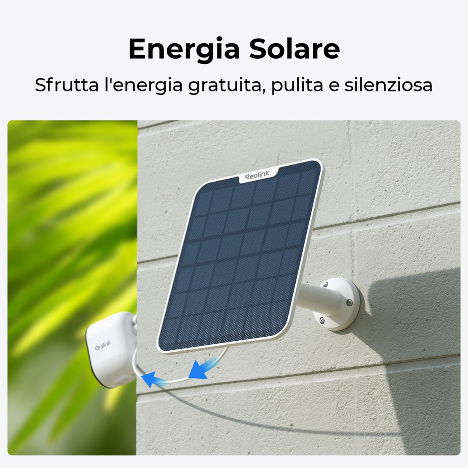 Pannello solare e telecamera di sicurezza montati su un muro. Il pannello è collegato alla telecamera tramite cavo. Fogliame verde sullo sfondo.