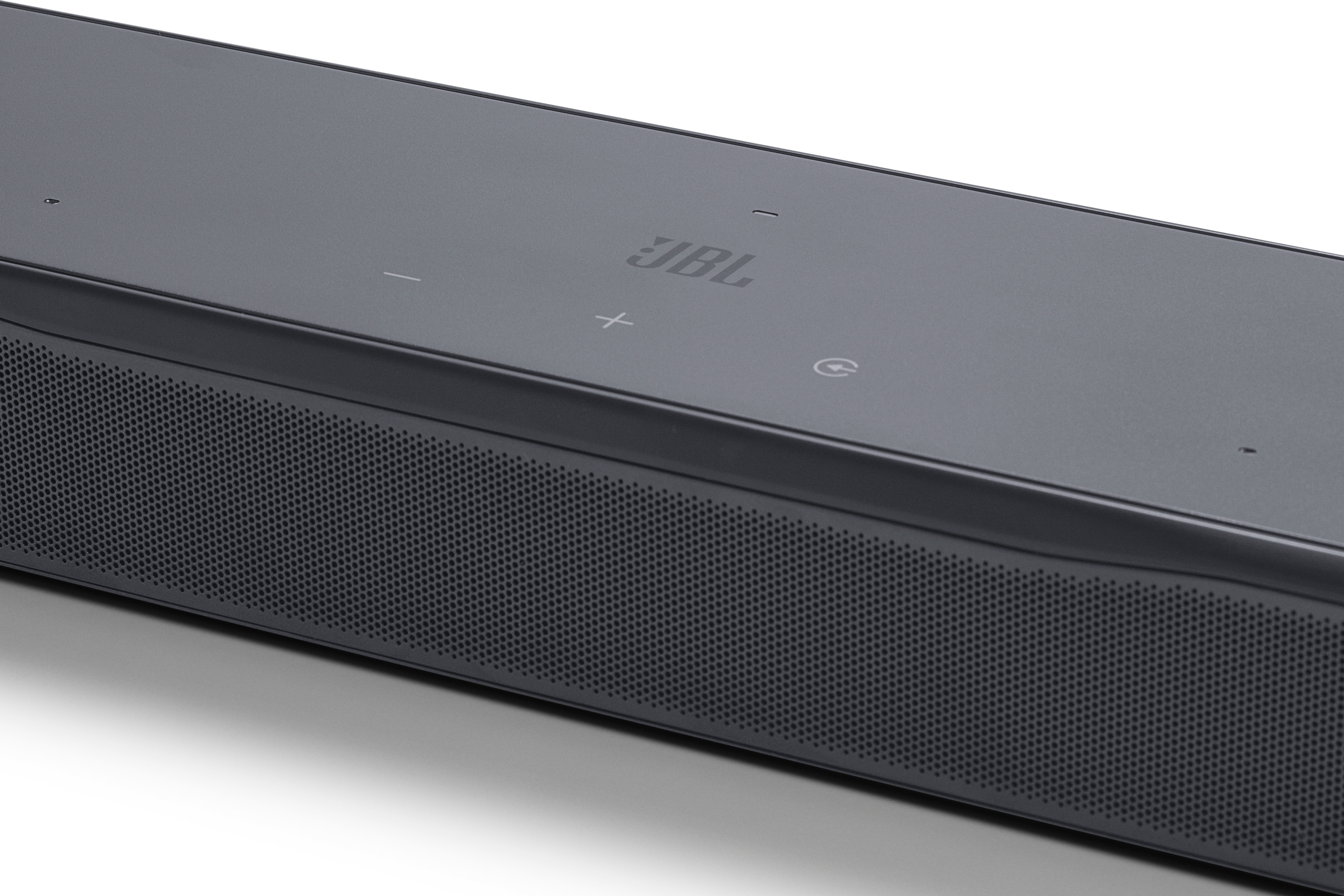 Nahaufnahme einer schwarzen JBL-Soundbar. Sie hat einen Mesh-Lautsprecher, Steuertasten und das JBL-Logo. Der Hintergrund ist weiß.
