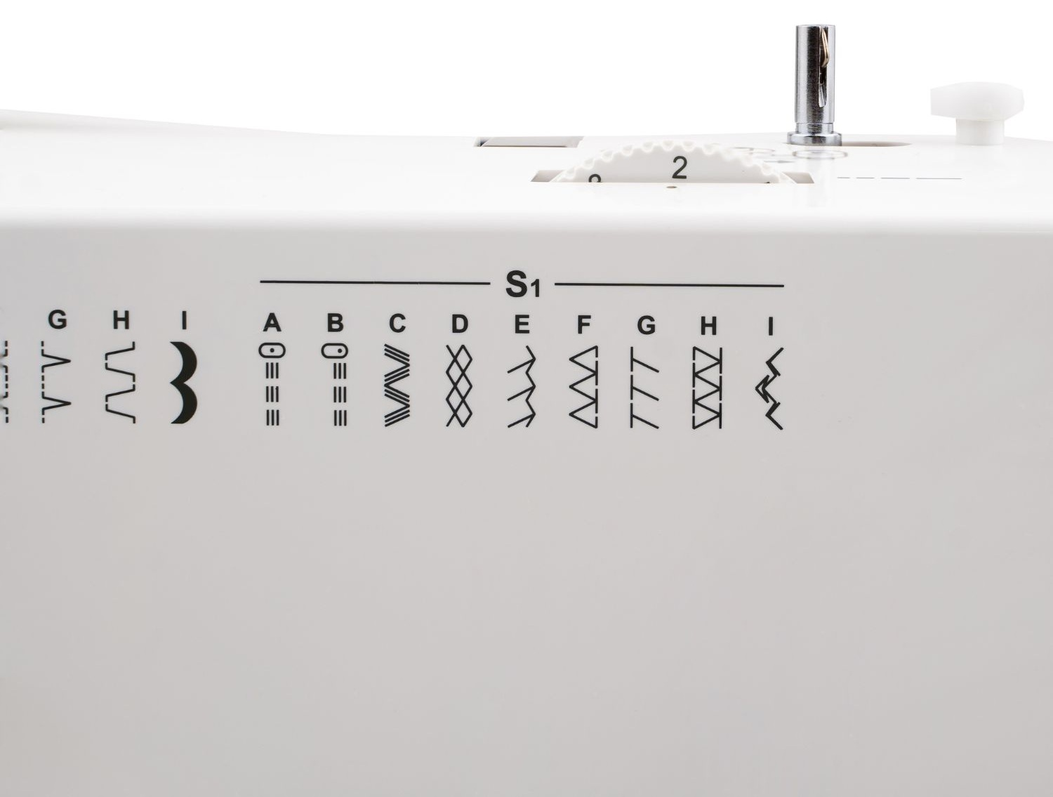 Biała maszyna do szycia ze wskaźnikami wzorów ściegów. Numery i symbole są wydrukowane na maszynie. Widoczny jest uchwyt na szpulę.