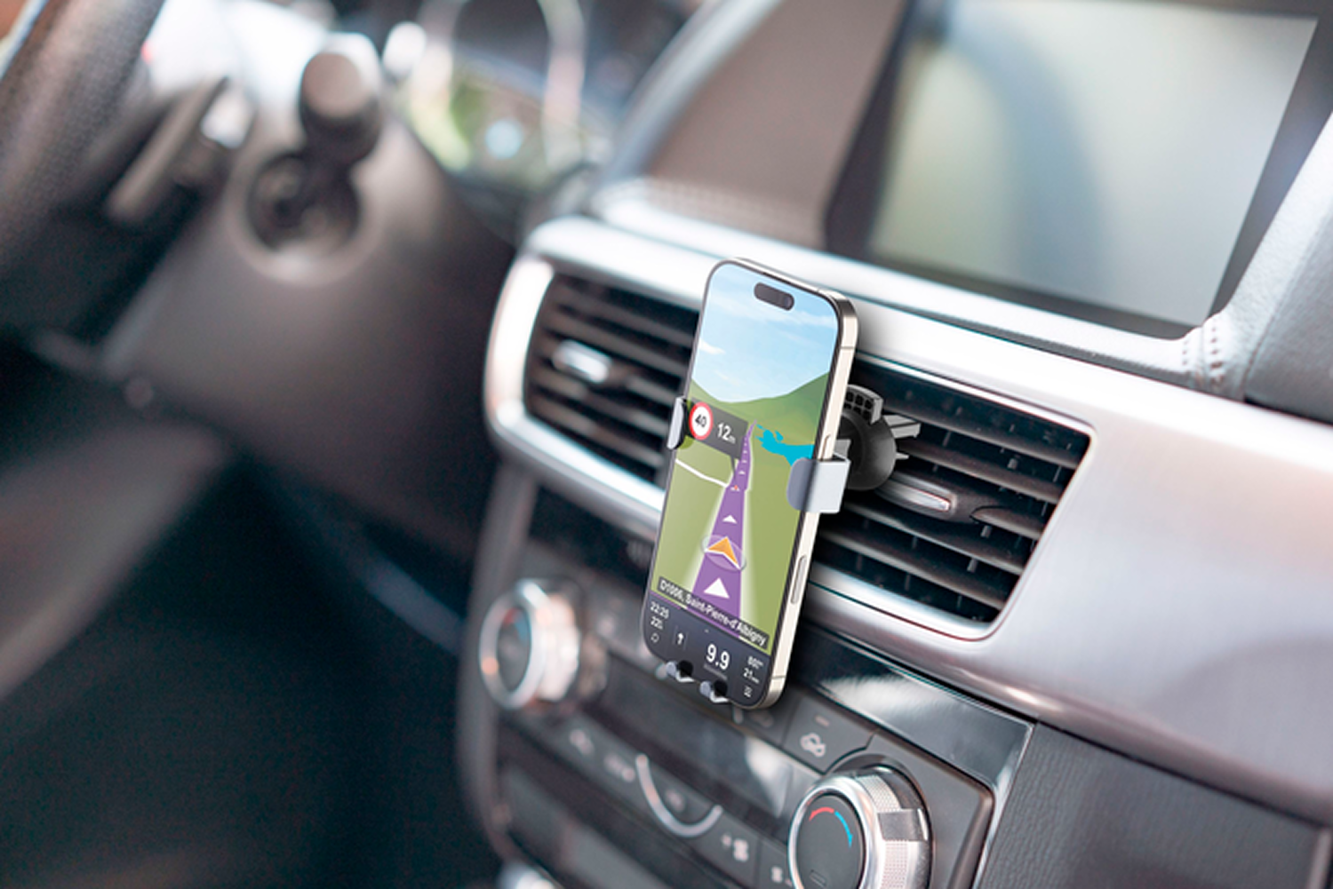Un smartphone mostrando una aplicación de navegación está montado en el salpicadero de un coche. Interior del coche visible.