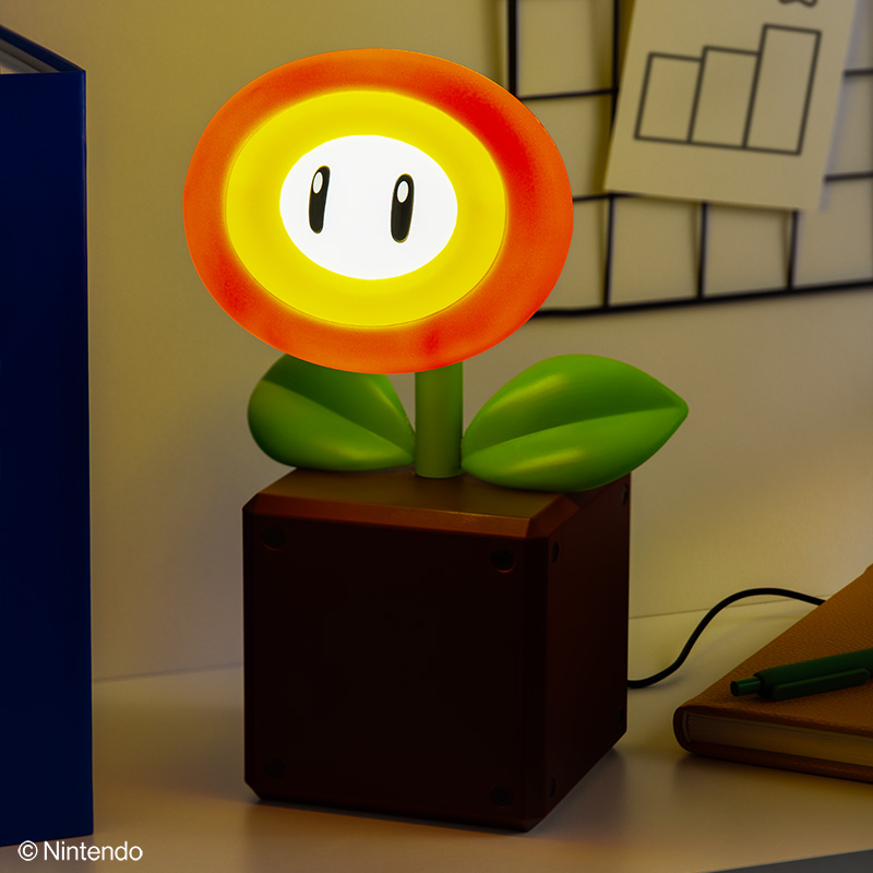 Eine Mario Piranha-Pflanzenlampe. Die Lampe steht in einem braunen Topf. Die Blume ist orange und gelb mit zwei schwarzen Augen und grünen Blättern.