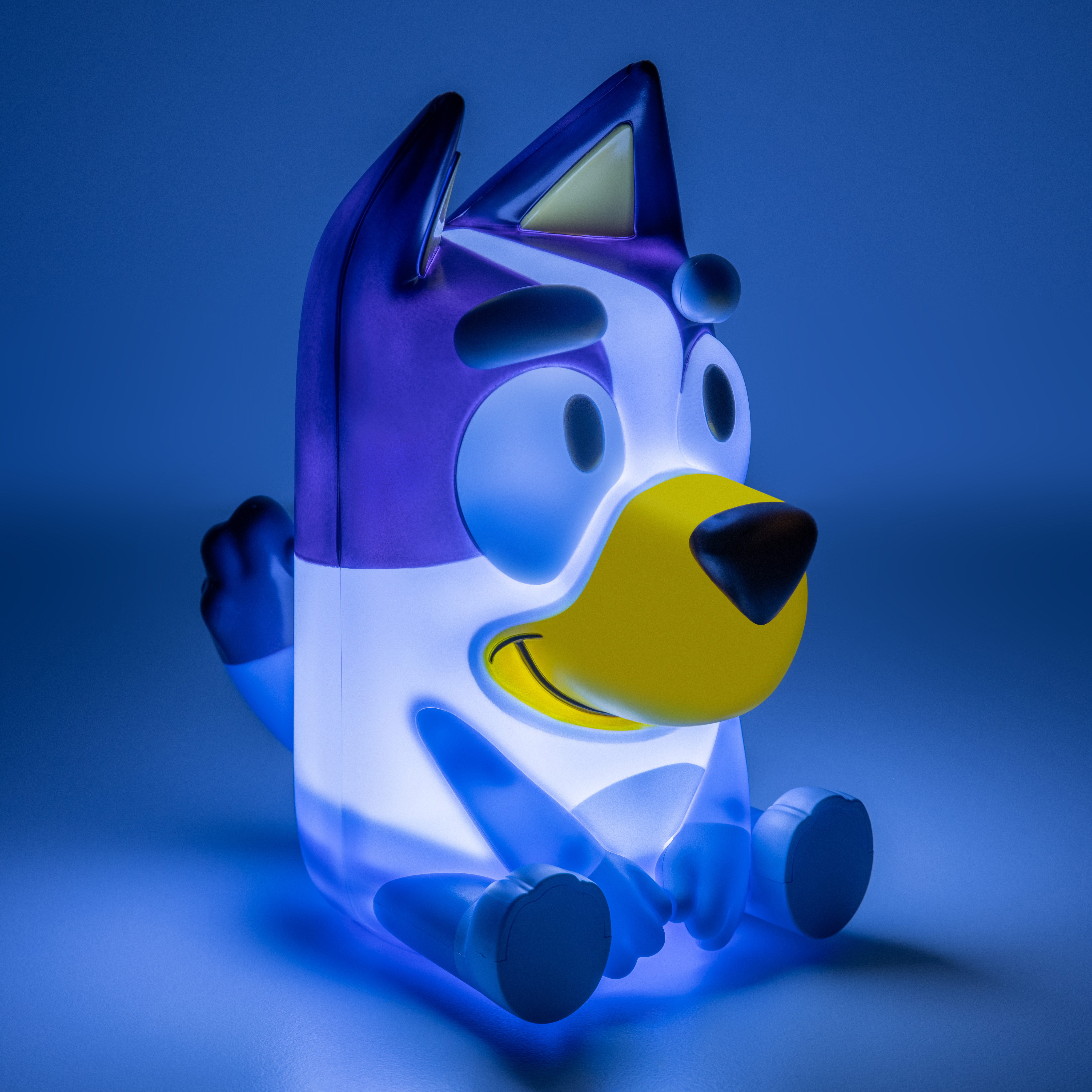 Bluey-Nachtlicht, eine Cartoon-Hundefigur. Blaue und weiße Farben mit gelber Schnauze, sitzt auf blauer Oberfläche.