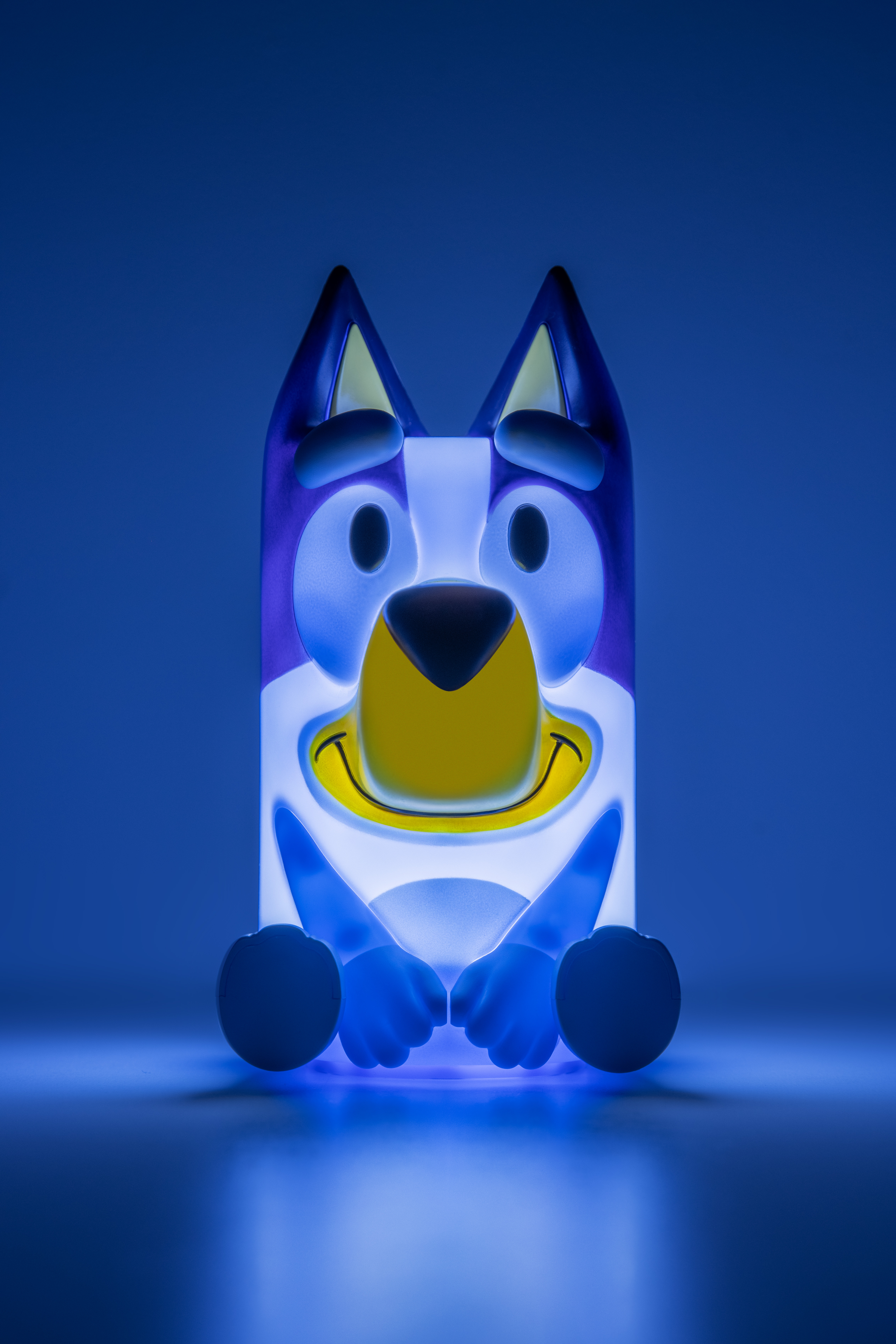 Ein blaues Bluey-Nachtlicht leuchtet mit gelbem Mund, lächelndem Gesicht und blauen Hundeohren.