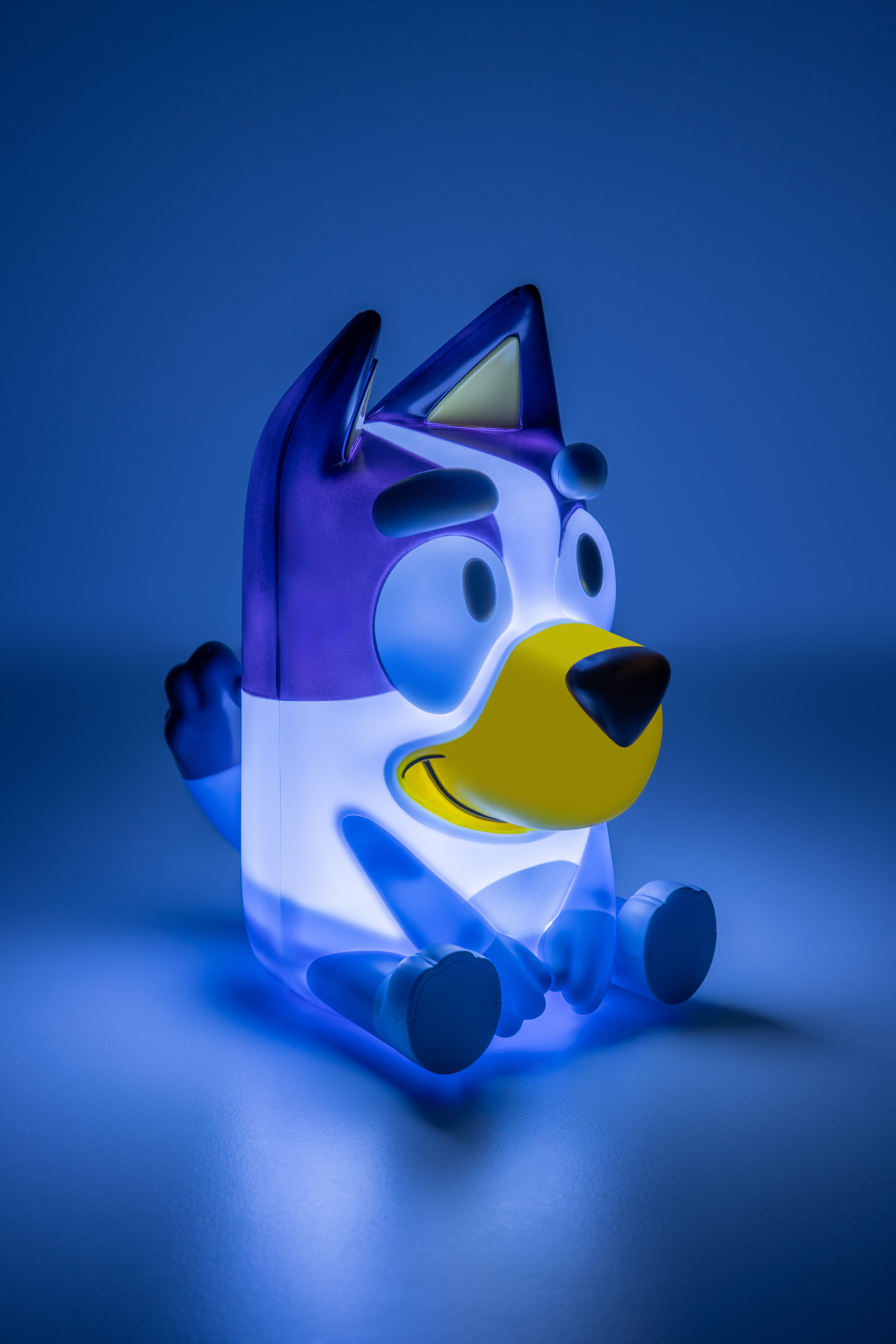 Eine Bluey-Lampe leuchtet blau. Es ist ein sitzender Hund mit blauen und weißen Farben und gelber Nase.