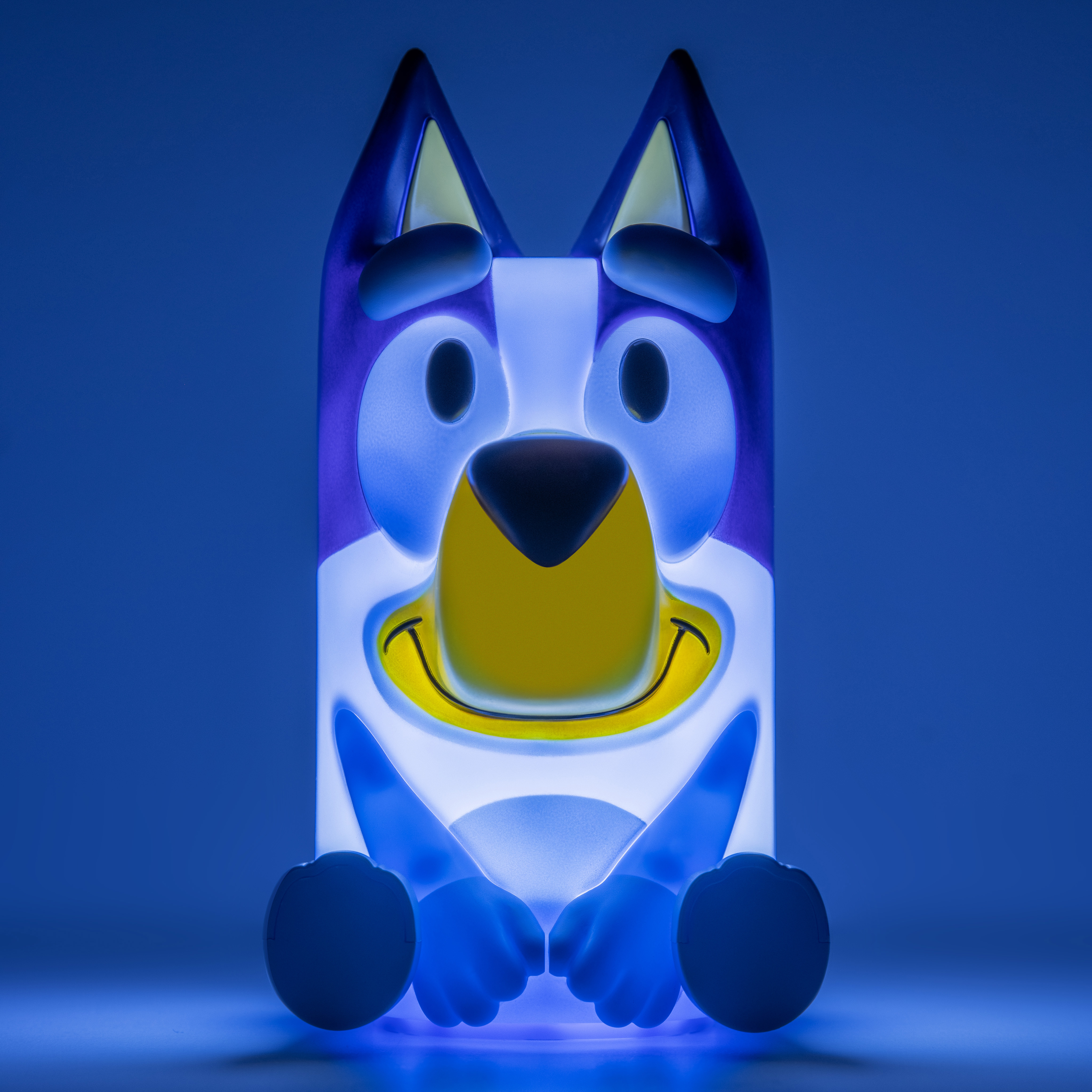 Bluey-Lampe in blau beleuchteter Umgebung. Sie hat ein lächelndes Gesicht, blaue Ohren und Arme. Der Hintergrund ist blau.