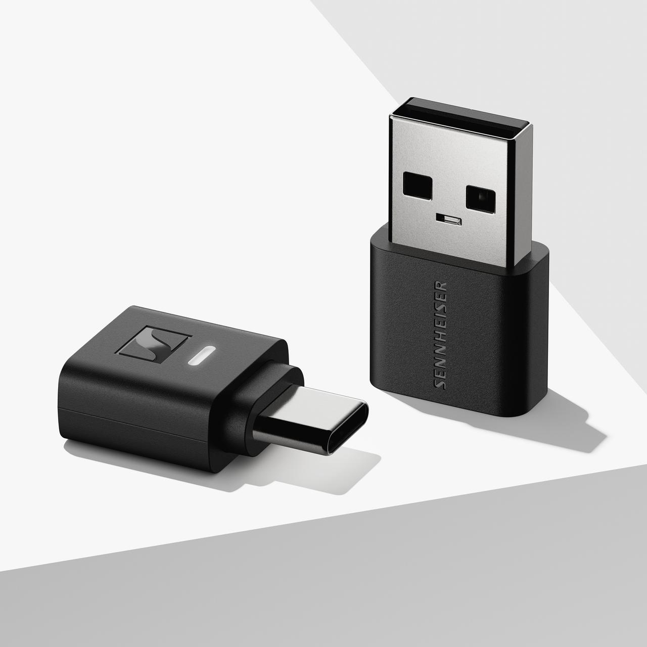 Két fekete Sennheiser USB-adapter. Egy USB-A-val, a másik USB-C-vel. Mindkettő fehér felületen.