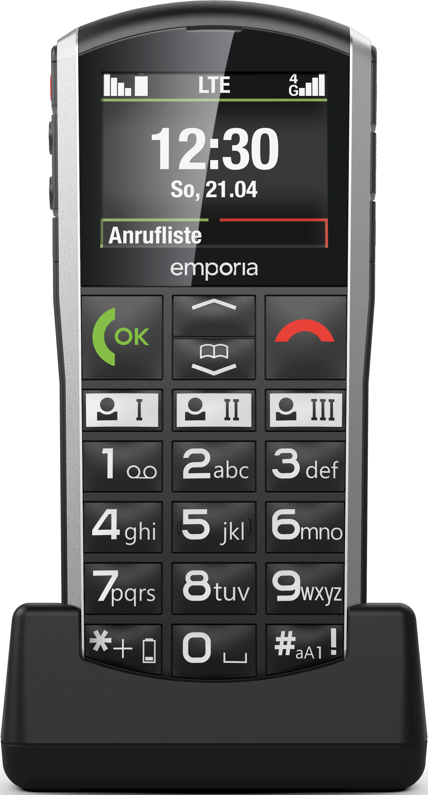 Un téléphone portable noir avec de gros boutons. L'écran affiche l'heure et la date. Il est dans un socle de chargement.