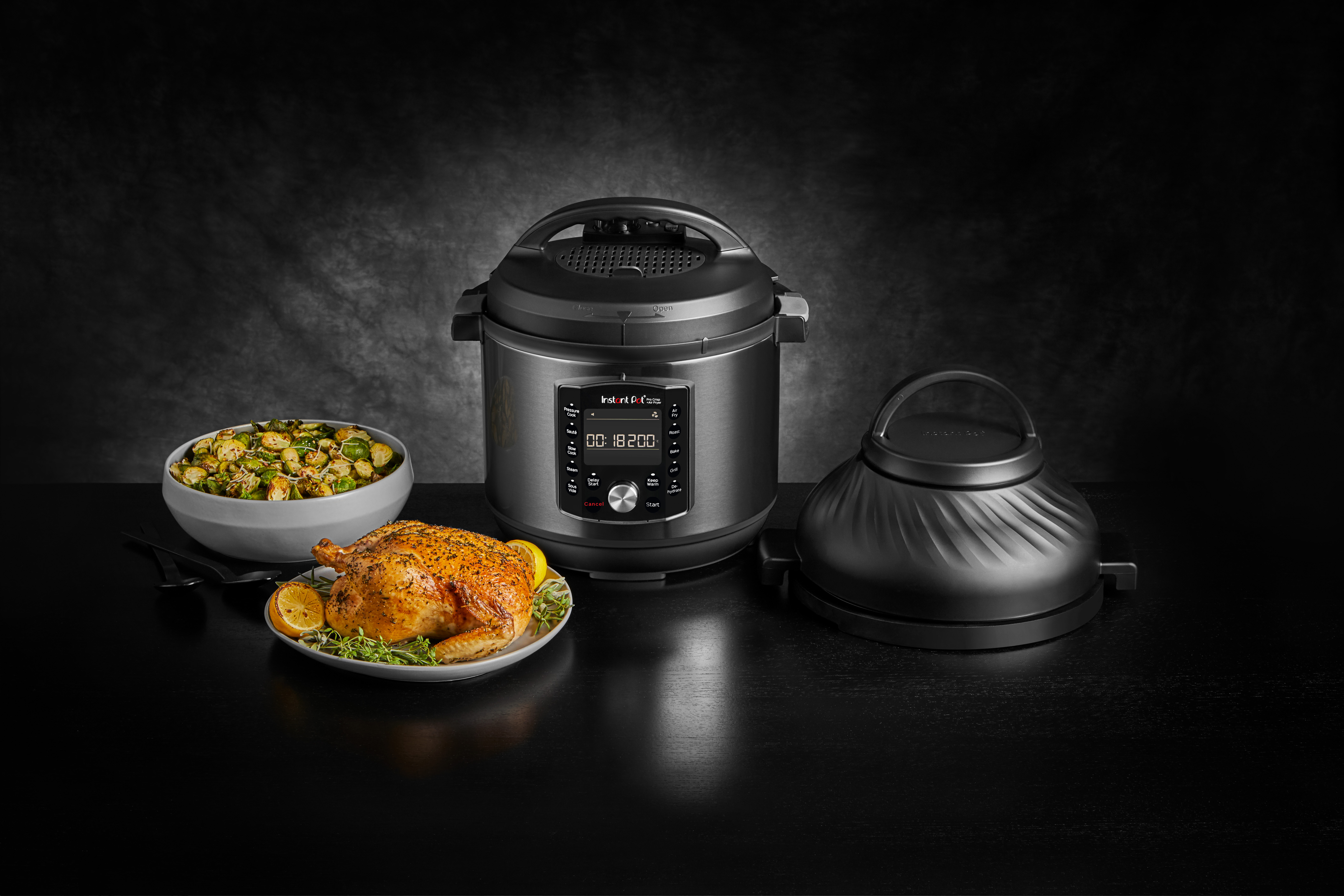 Ein Instant Pot mit Brathähnchen, Rosenkohl und Airfryer-Deckel auf dunkler Oberfläche, schwarzer Hintergrund.