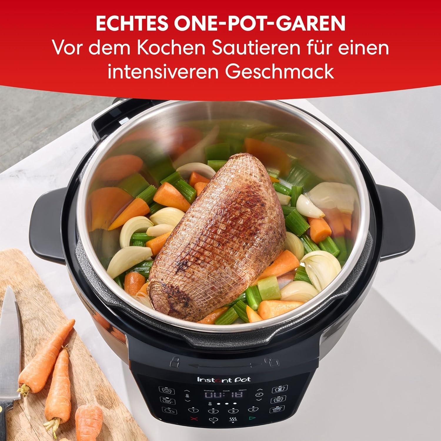 Ein Instant Pot mit Fleisch und Gemüse. Karotten und ein Messer liegen auf einem Holzbrett.