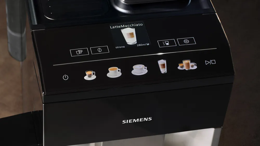 Egy fekete Siemens kávéfőző vezérlőpultja kávéfajtákat mutat: latte macchiato, espresso, cappuccino. Különböző ikonok és gombok láthatók.