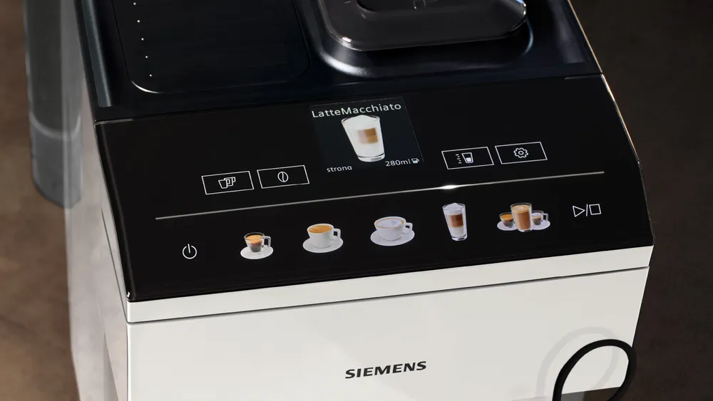 Egy Siemens kávéfőző fekete-fehér dizájnnal. A kijelző Latte Macchiatót mutat. Több kávéopció látható.