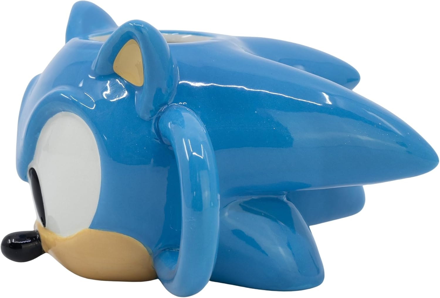 Una taza azul de cerámica de Sonic the Hedgehog, con ojo blanco, nariz negra y hocico marrón claro. Tiene un asa y una oreja azules.